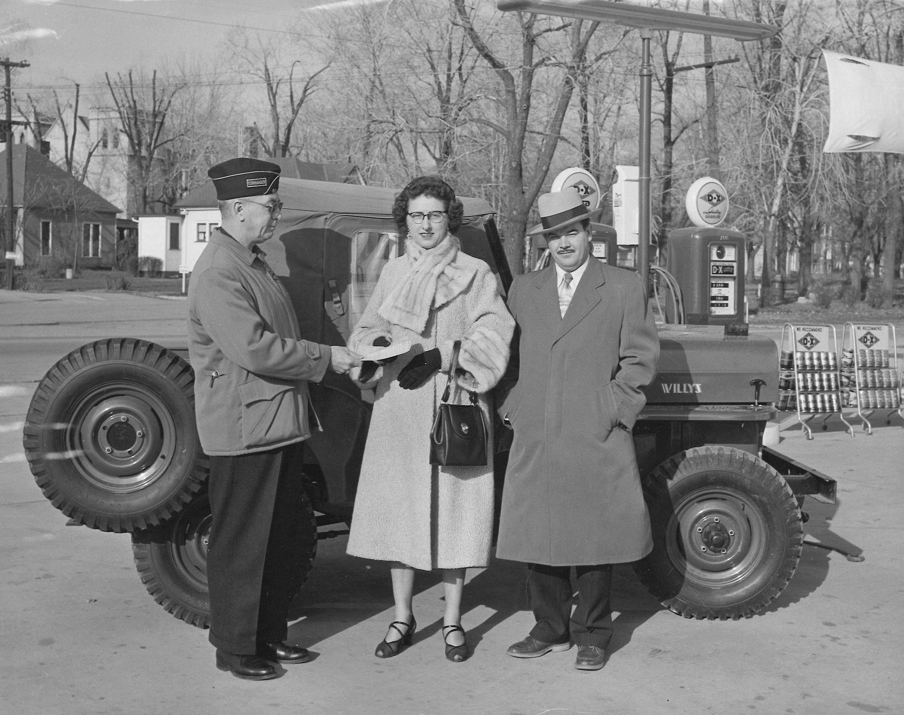 Gas station attendant with couple by vintage jeep