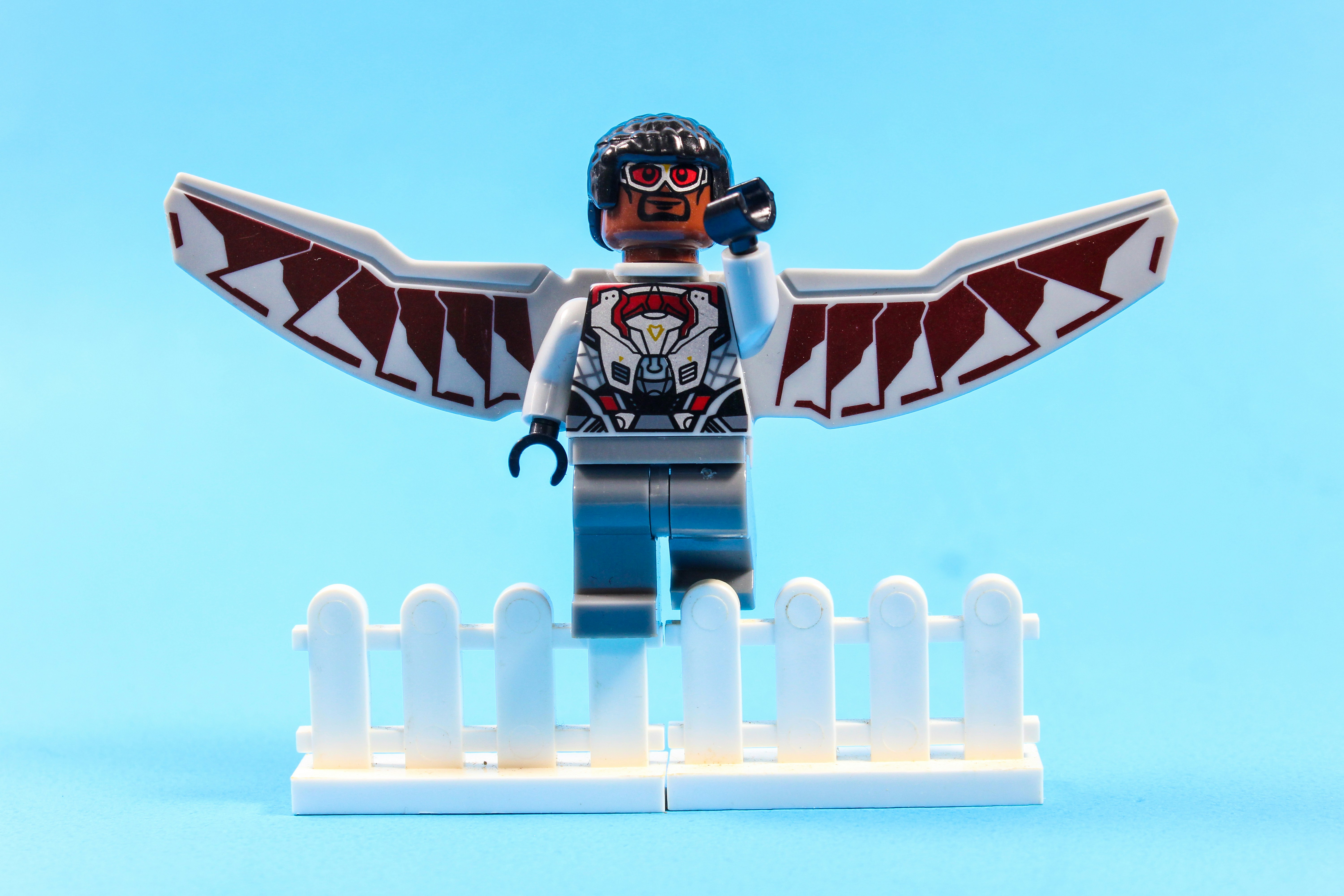 Lego falcon with wings standing behind white fence