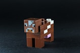 A brown minecraft cow toy on a black background