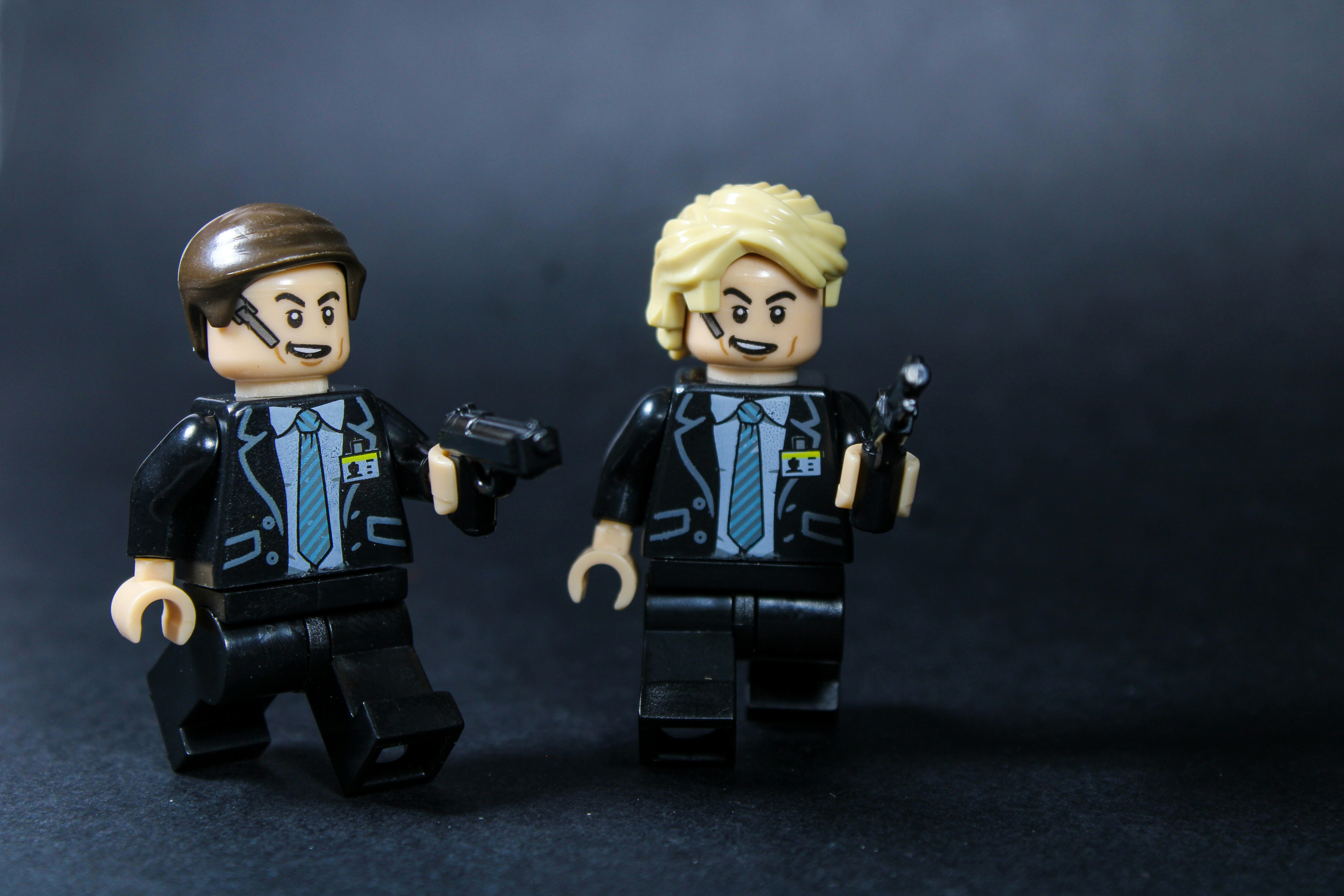 Two lego figures in suits holding accessories.