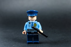 Lego police officer holding a baton against dark background
