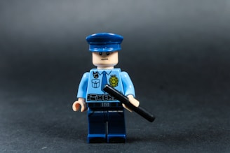 Lego police officer holding a baton against dark background