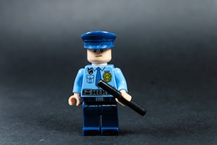 Lego police officer holding a baton against dark background
