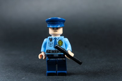 Lego police officer holding a baton against dark background