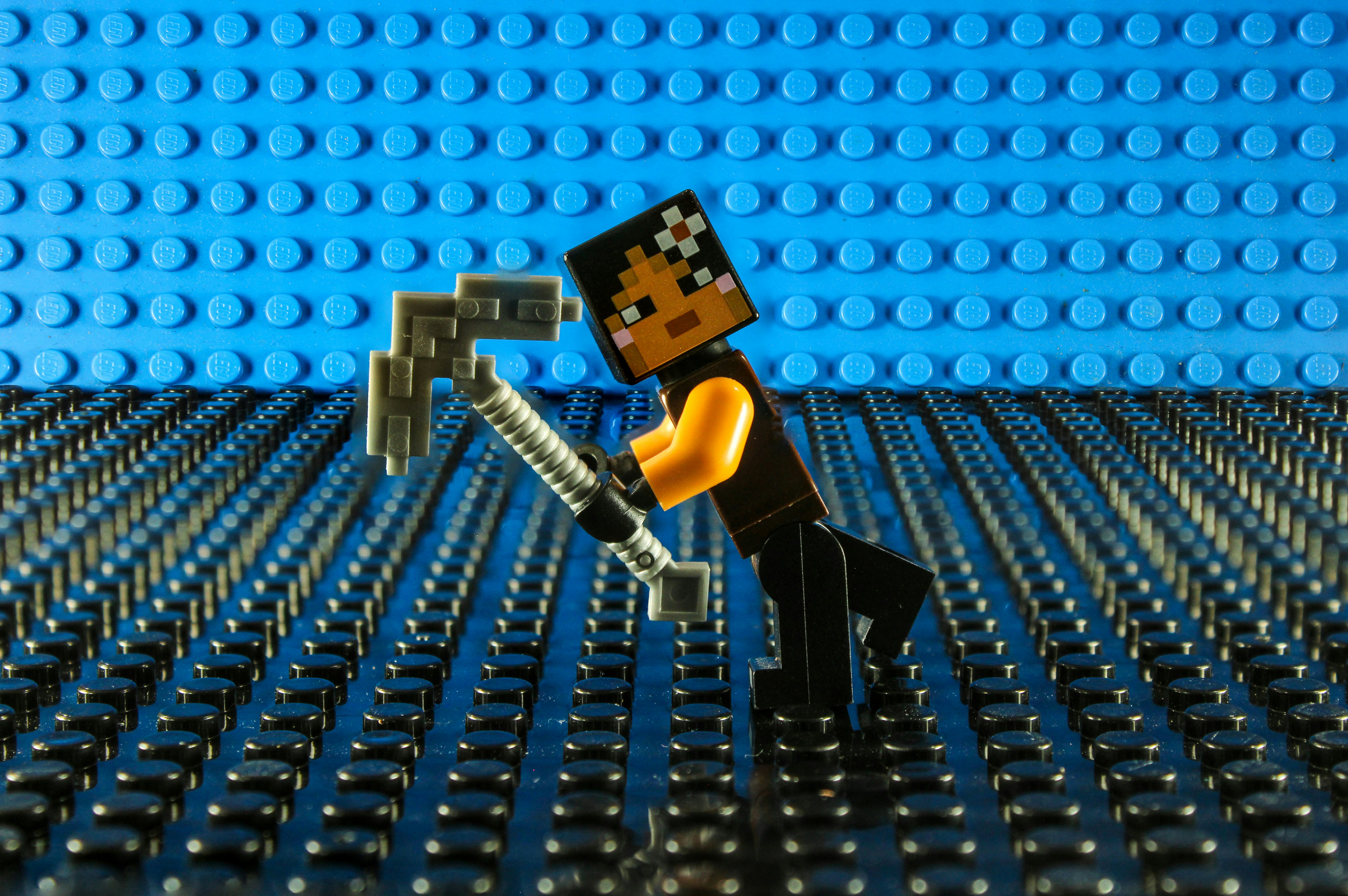 Lego figure with pickaxe on blue background.