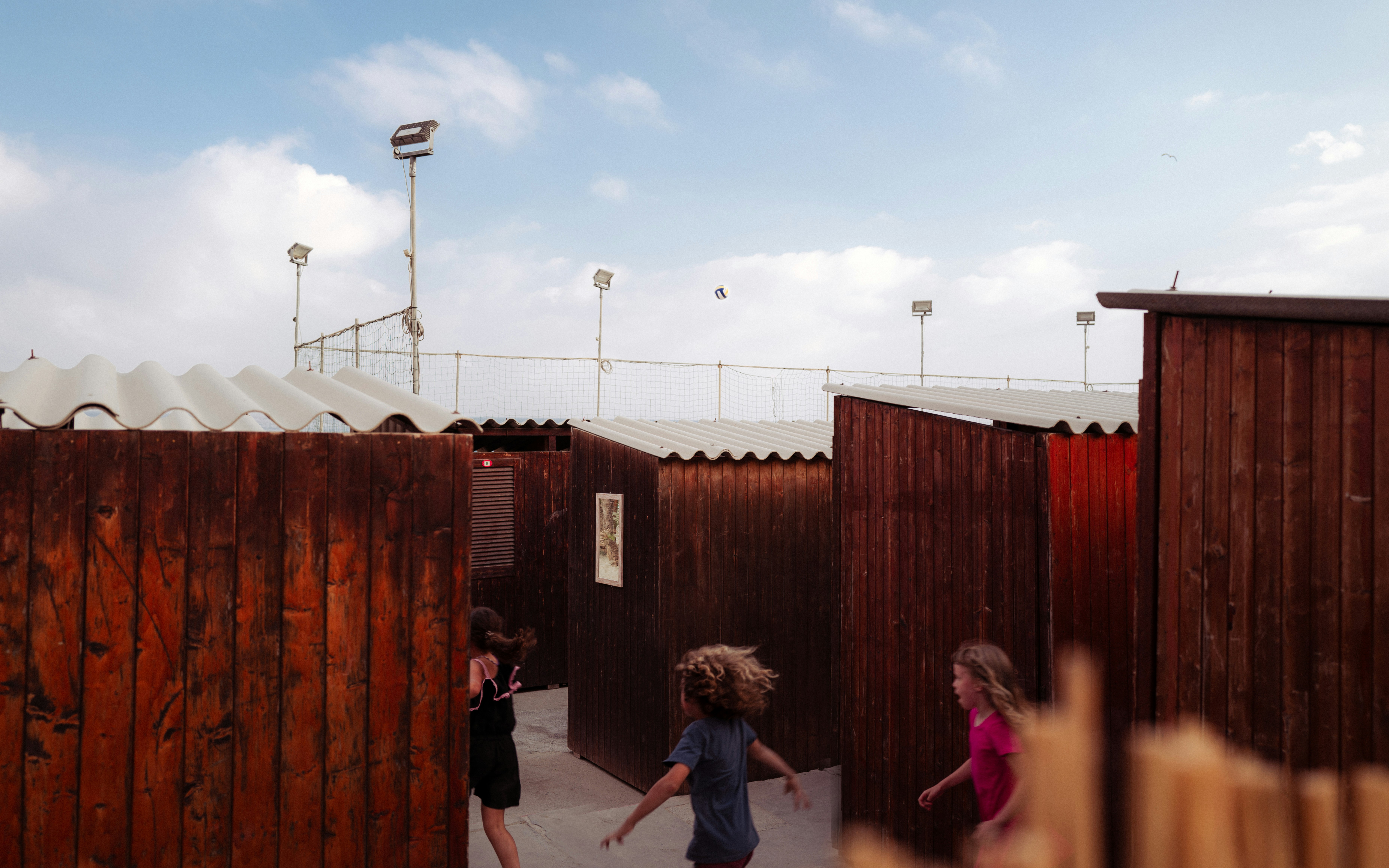 Children running through a wooden maze on a cloudy day.