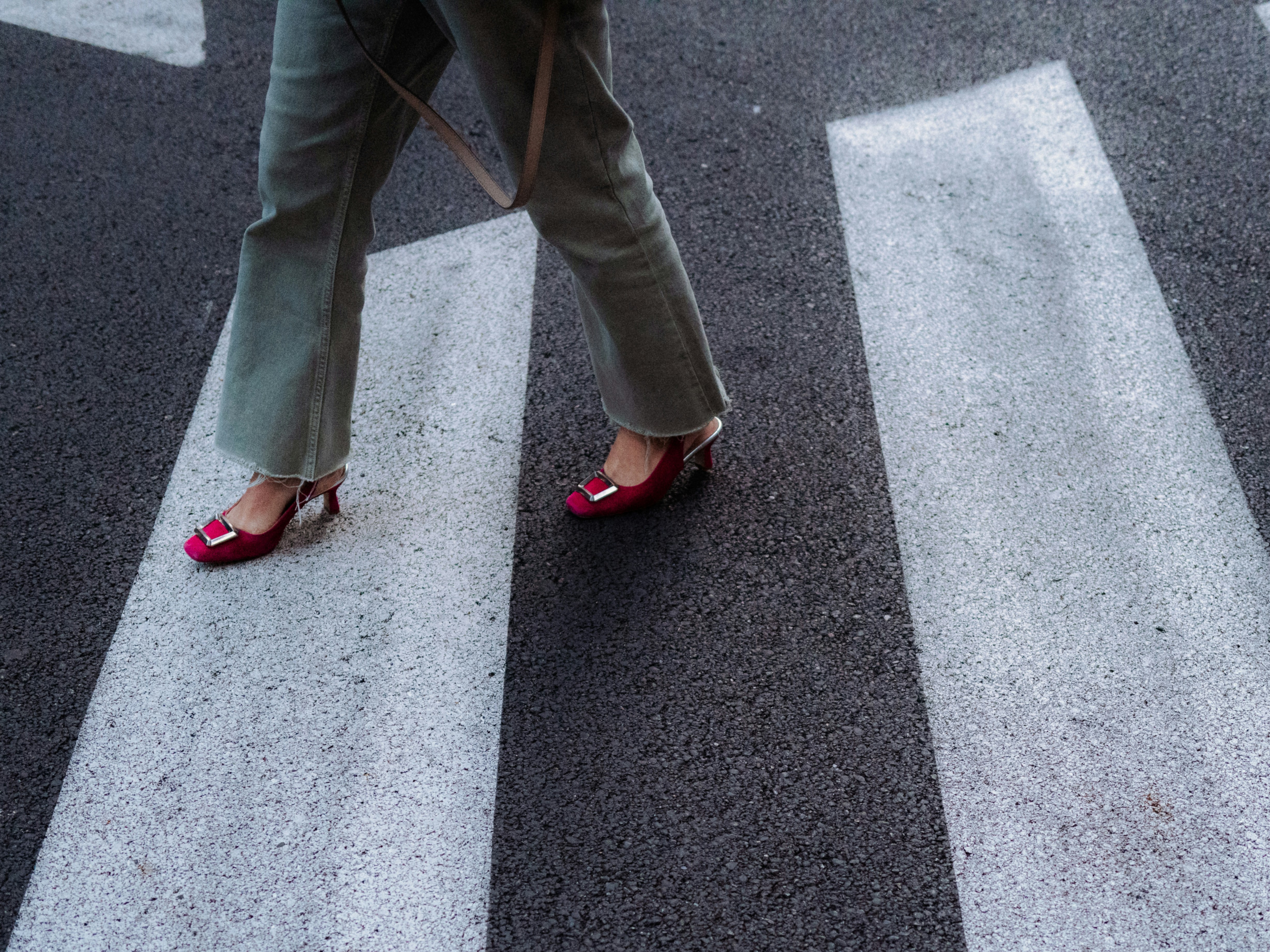 Person walking across a crosswalk in stylish shoes.