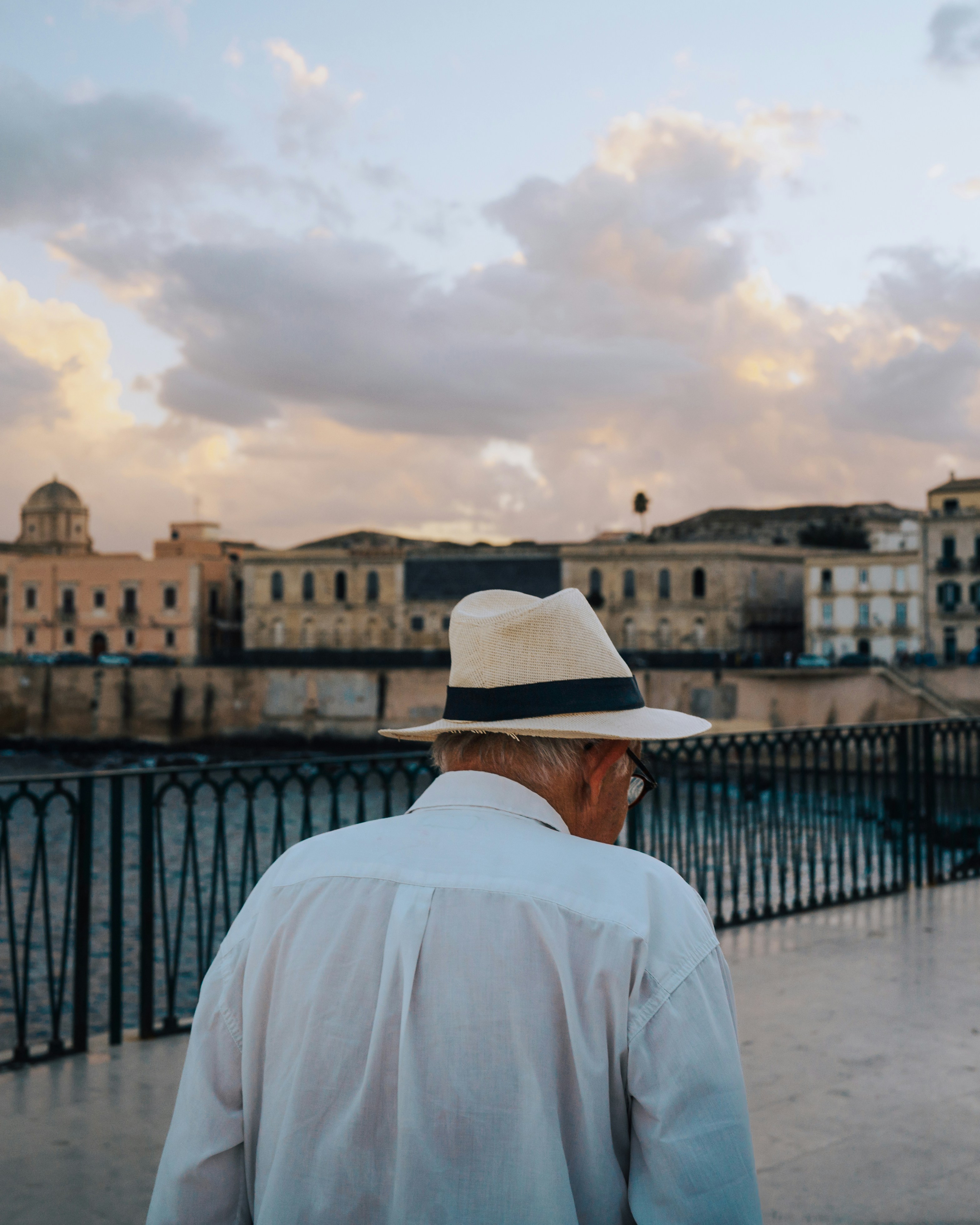 Man in hat walks by old buildings at sunset