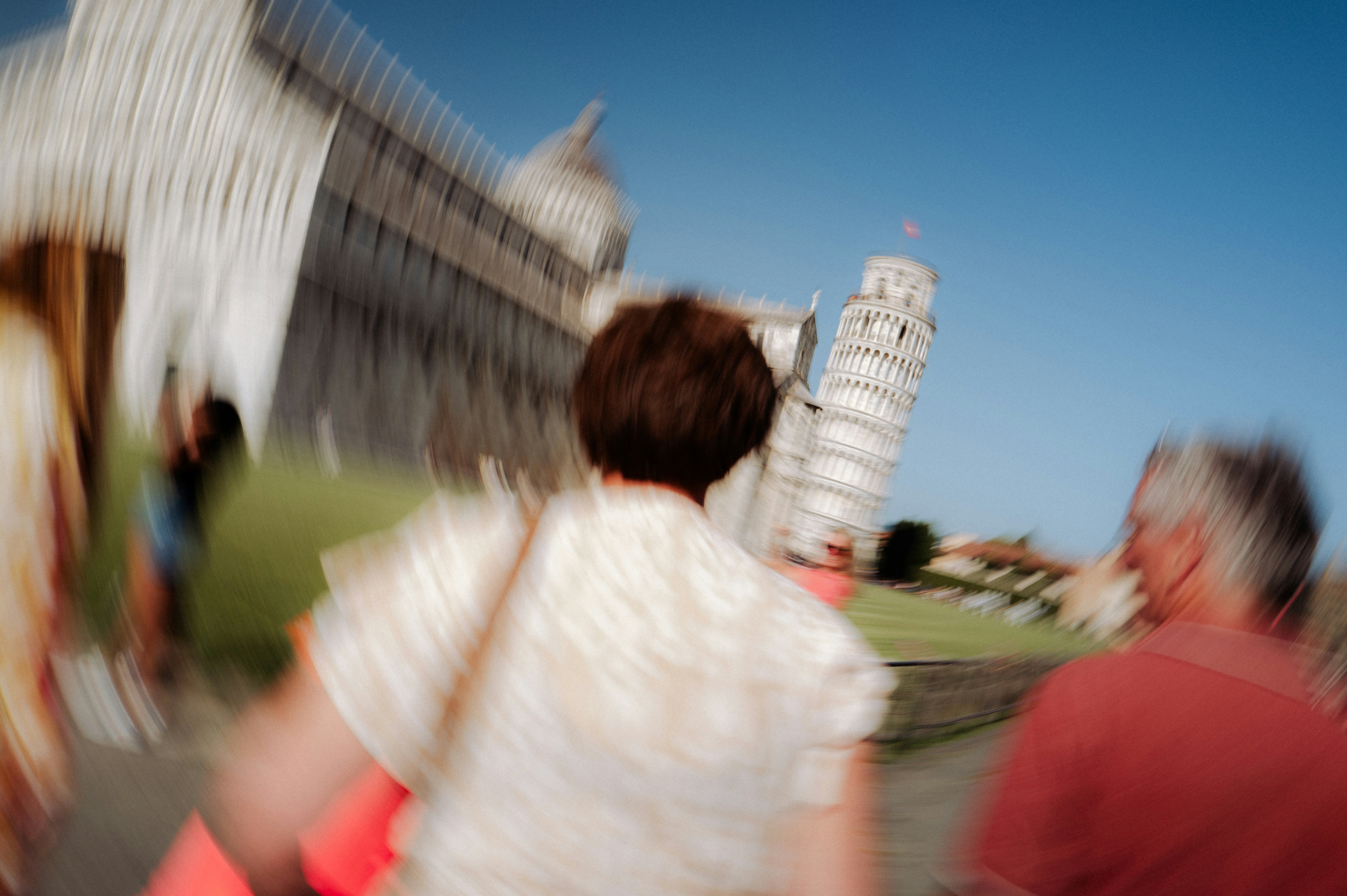Tourists walk towards the leaning tower of pisa.