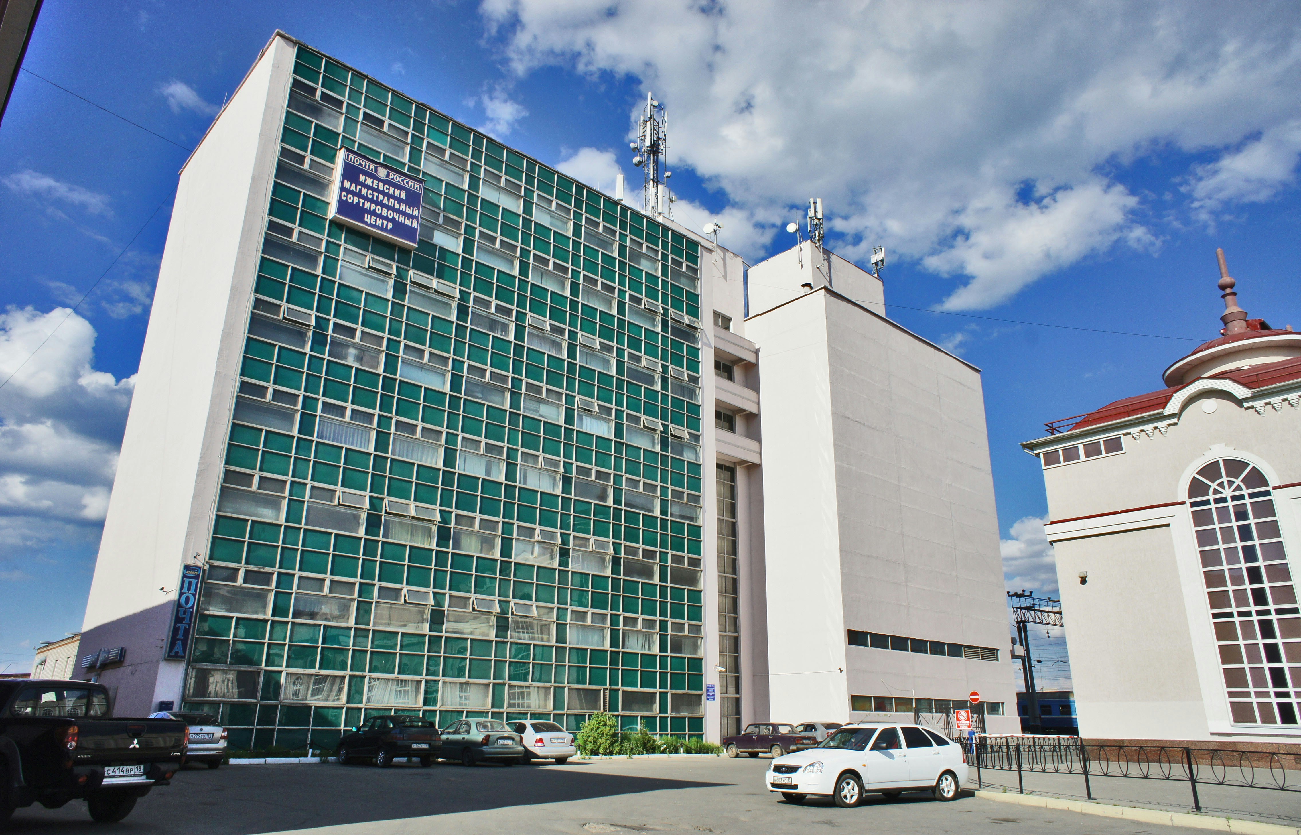 Modern white and green building with cars outside.