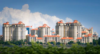 Apartment buildings with red tile roofs under blue sky.
