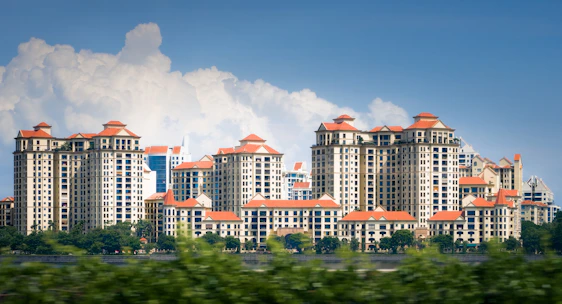 Apartment buildings with red tile roofs under blue sky.
