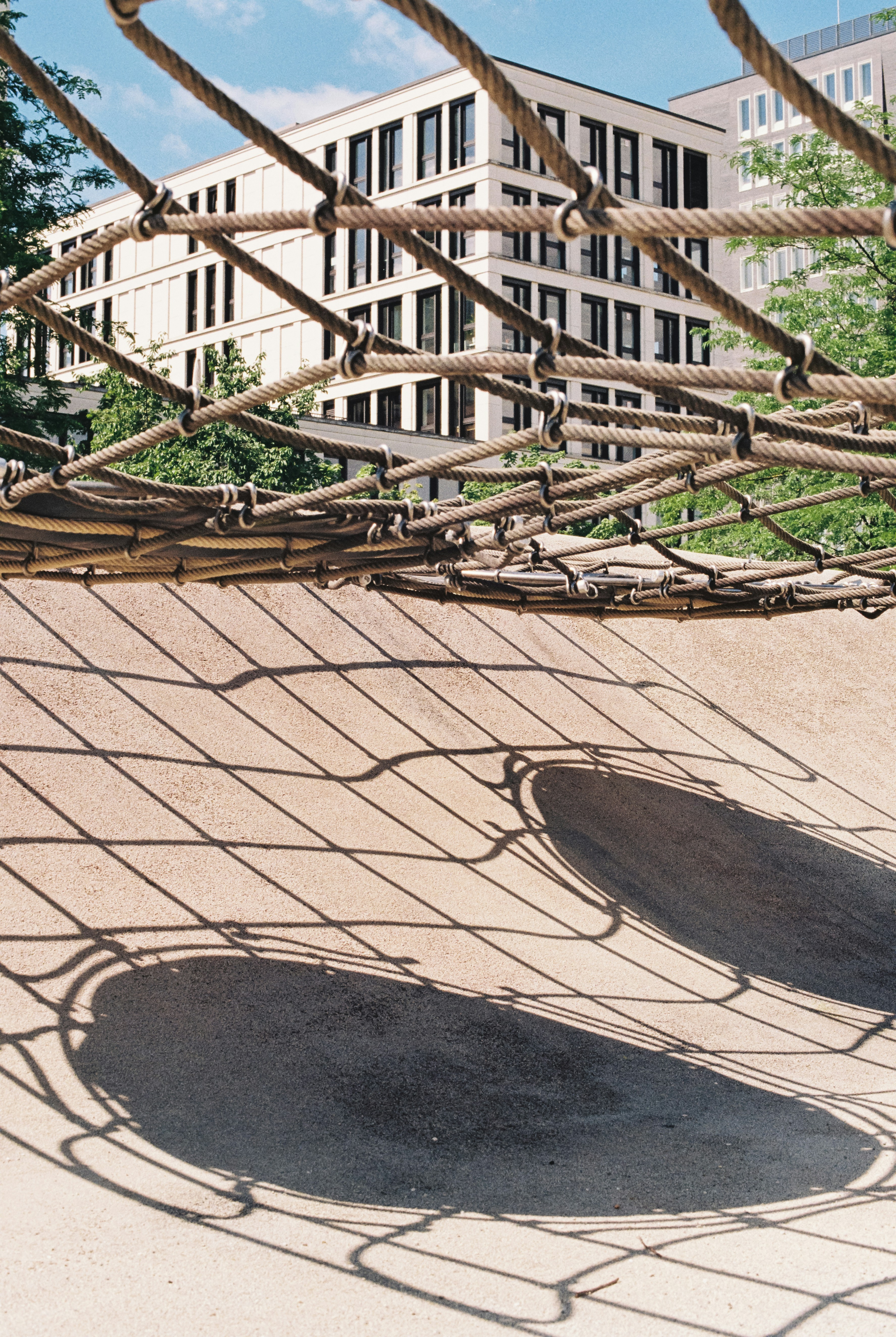Rope net casting shadows on playground surface