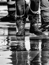 Close-up of muddy boots reflected in wet ground