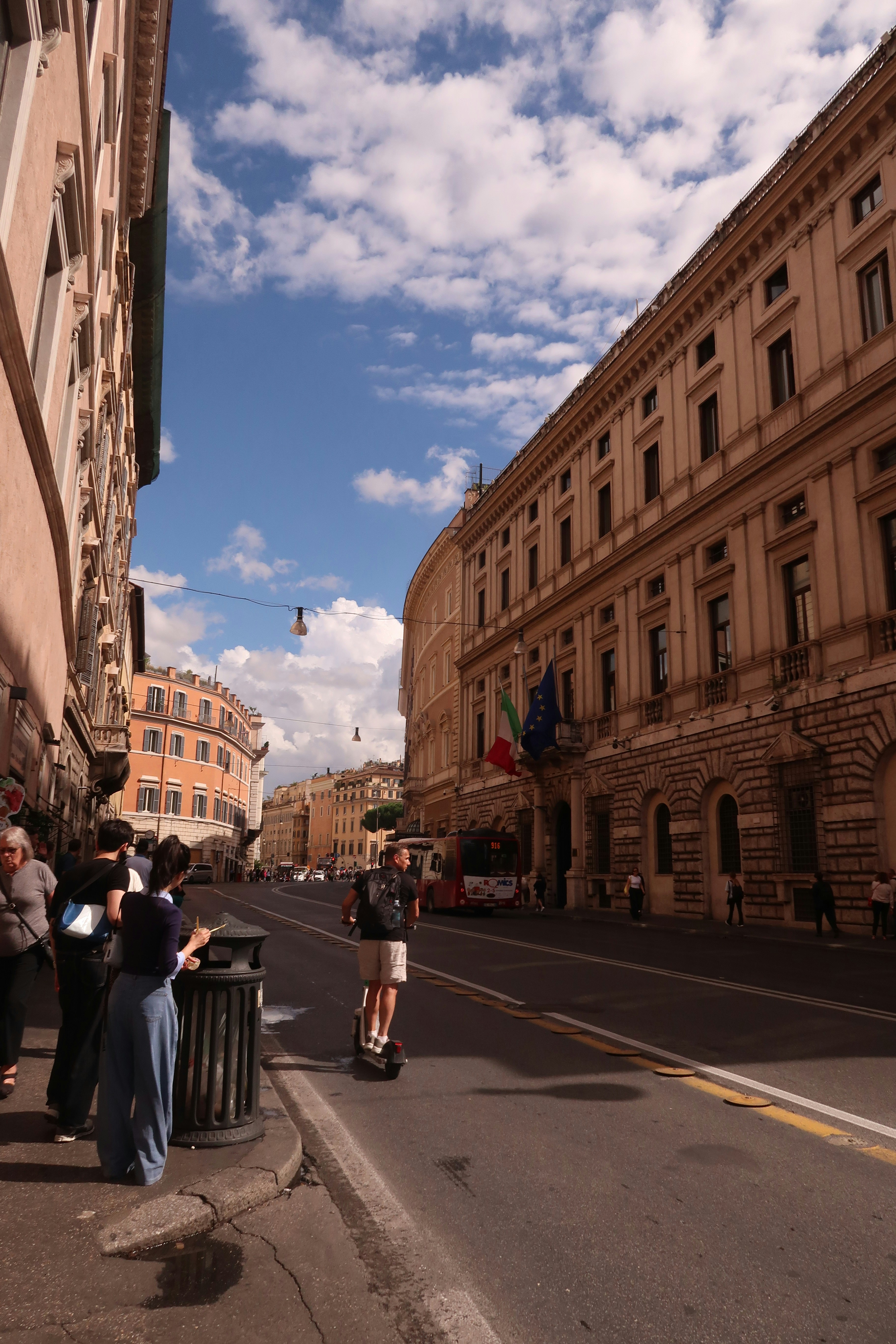 People on a street with historic buildings and flags.