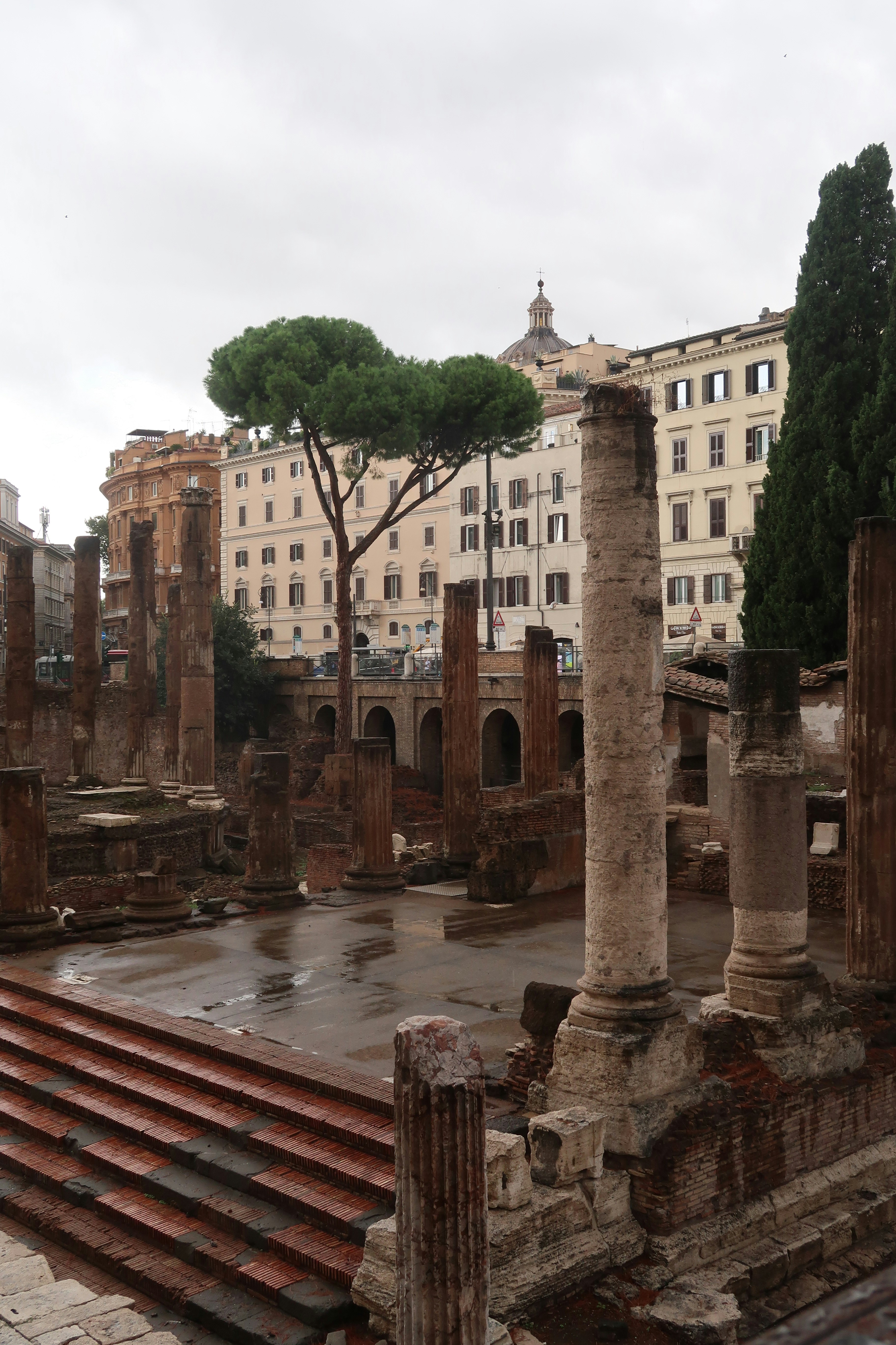 Ancient ruins with modern buildings in the background.
