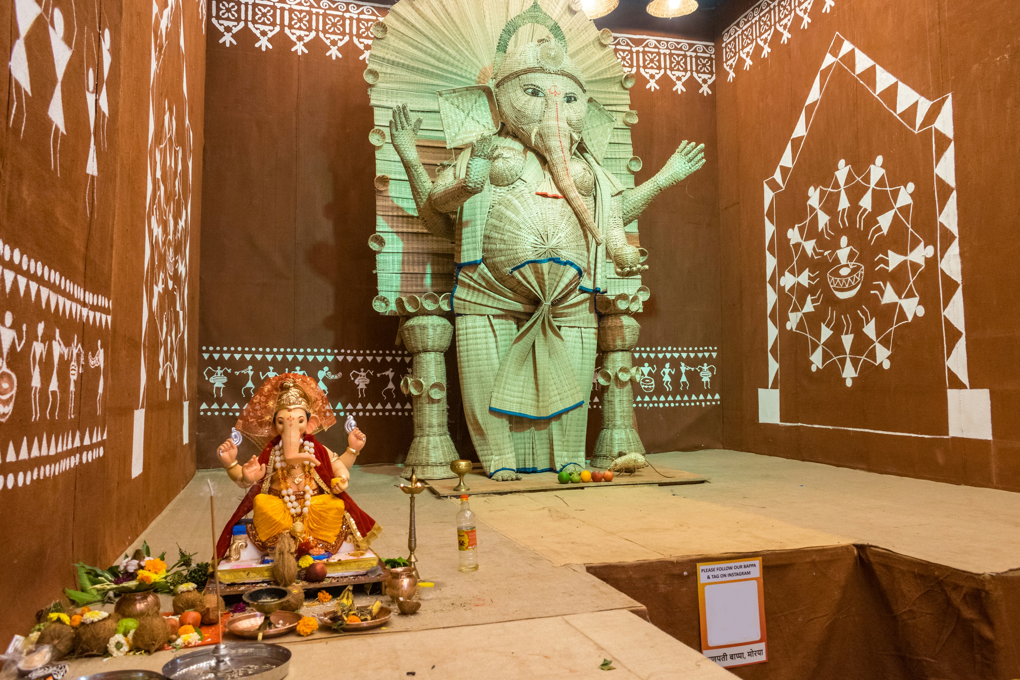 Two ganesh idols decorated with offerings and art