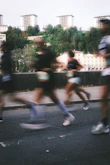 Runners race on a street with buildings behind.