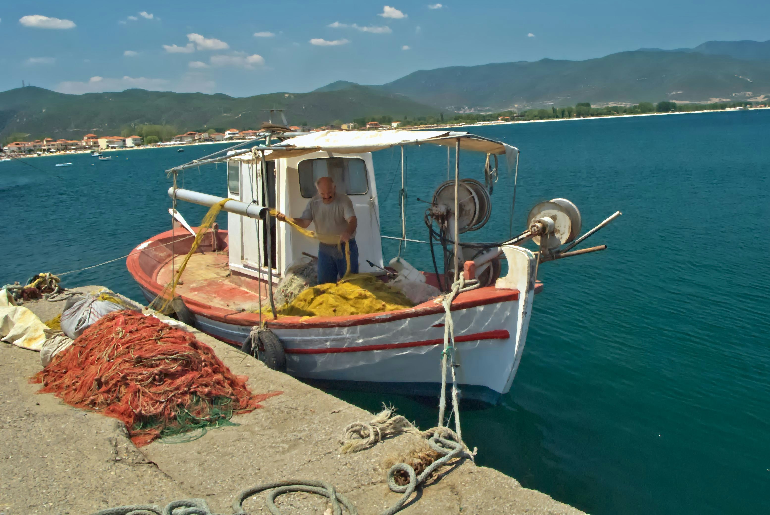 A small fishing boat docked by a pier with nets.