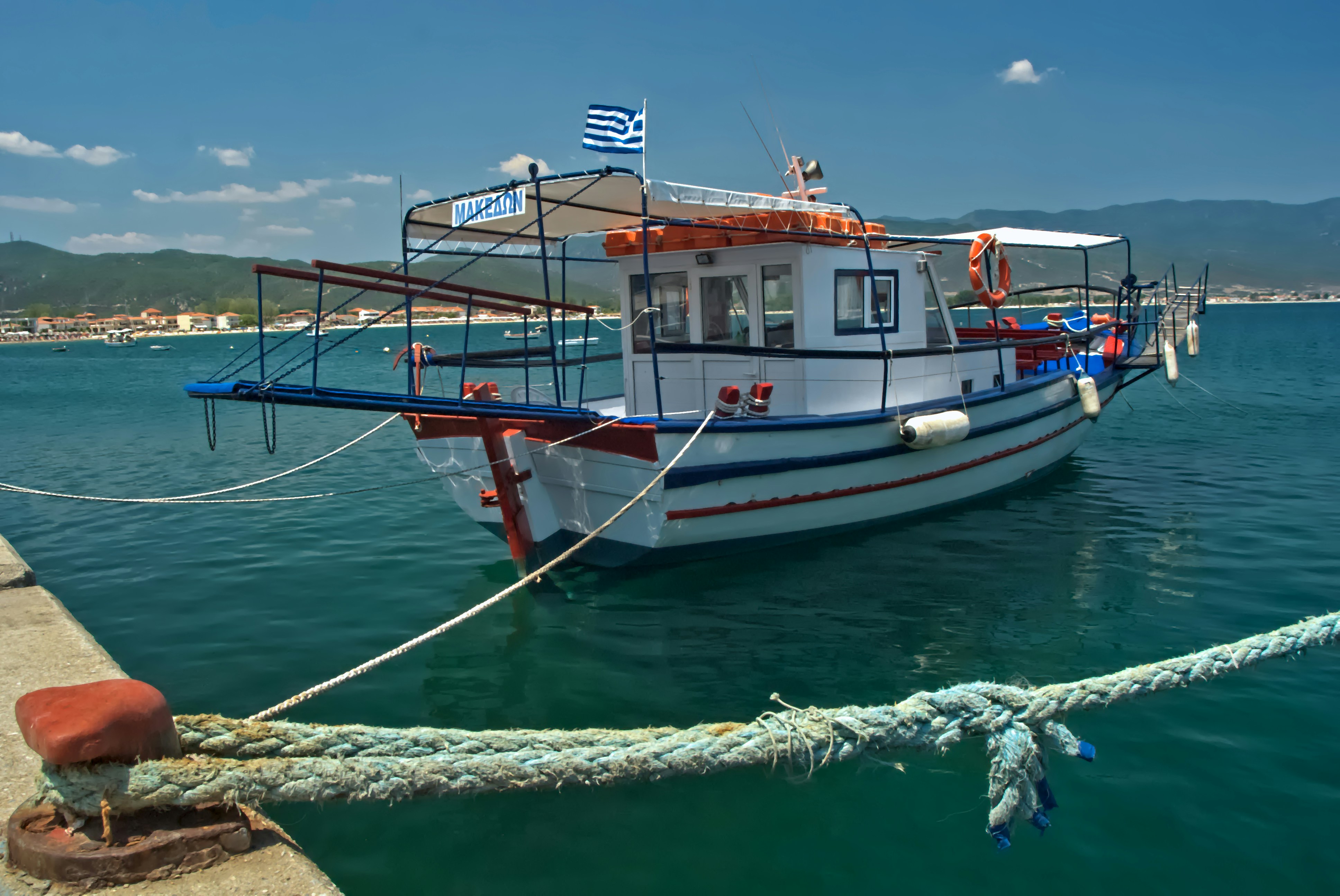 A white fishing boat docked in clear blue water.