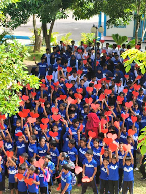 Students hold red heart shapes outdoors