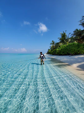 Person walking in shallow clear turquoise ocean water.