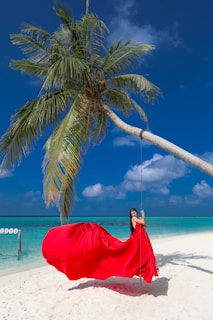 Woman in red dress on a swing under palm tree