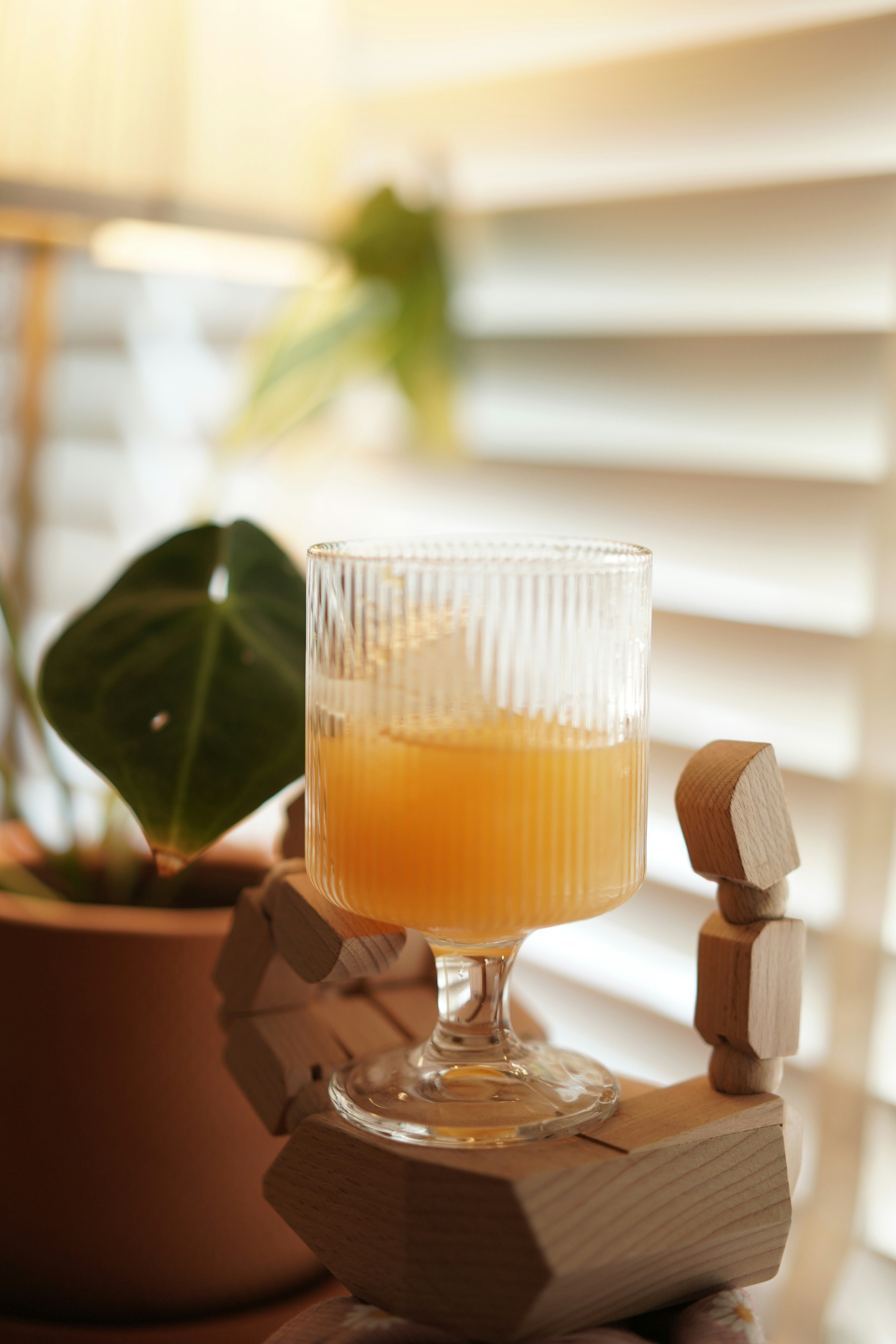 A glass of orange juice on a wooden hand.
