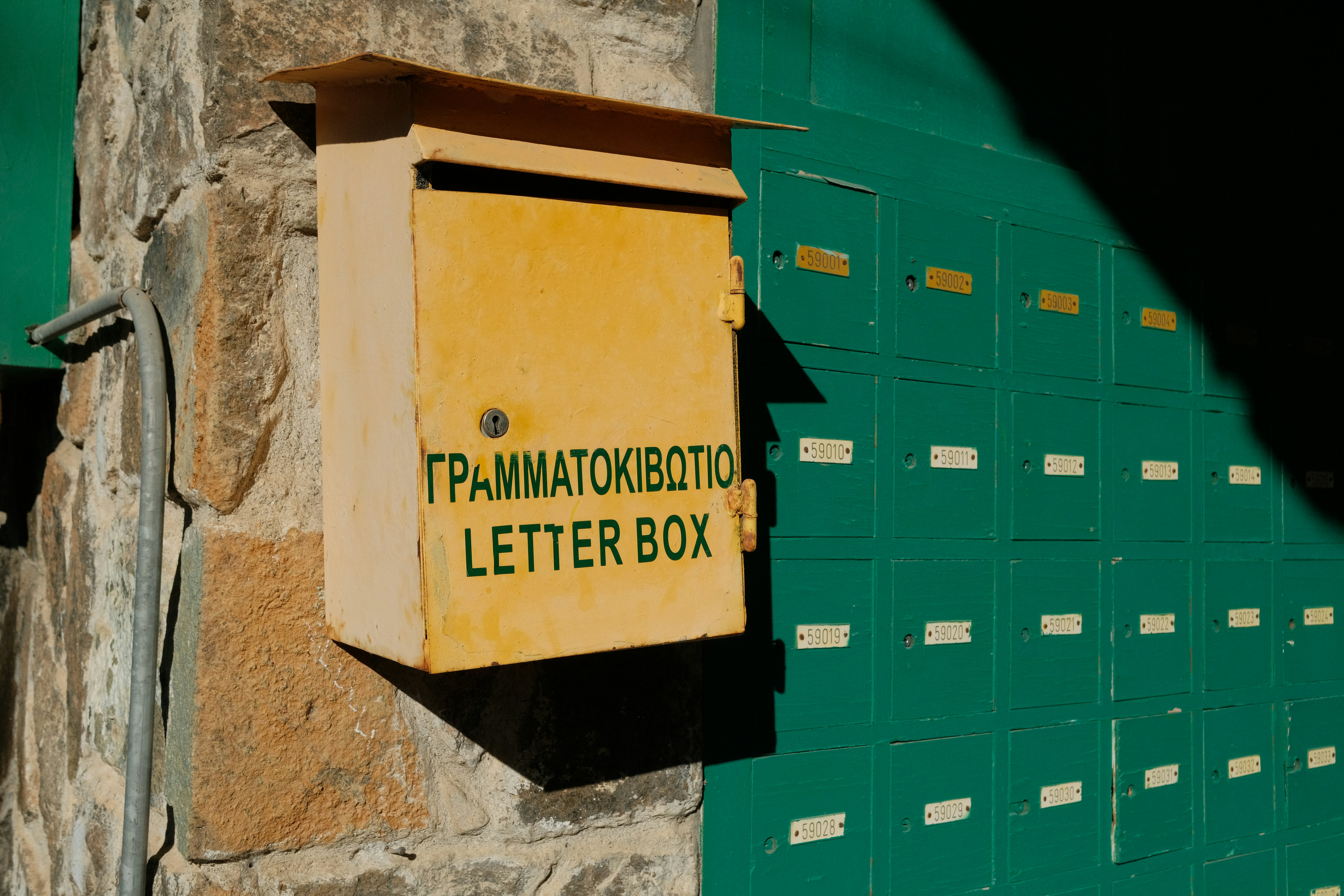 Gelber Briefkasten an Steinwand montiert