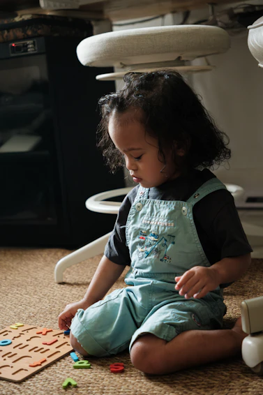 A young child plays with alphabet letters on the floor