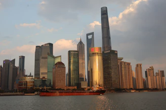 Modern skyscrapers and a cargo ship on the water.