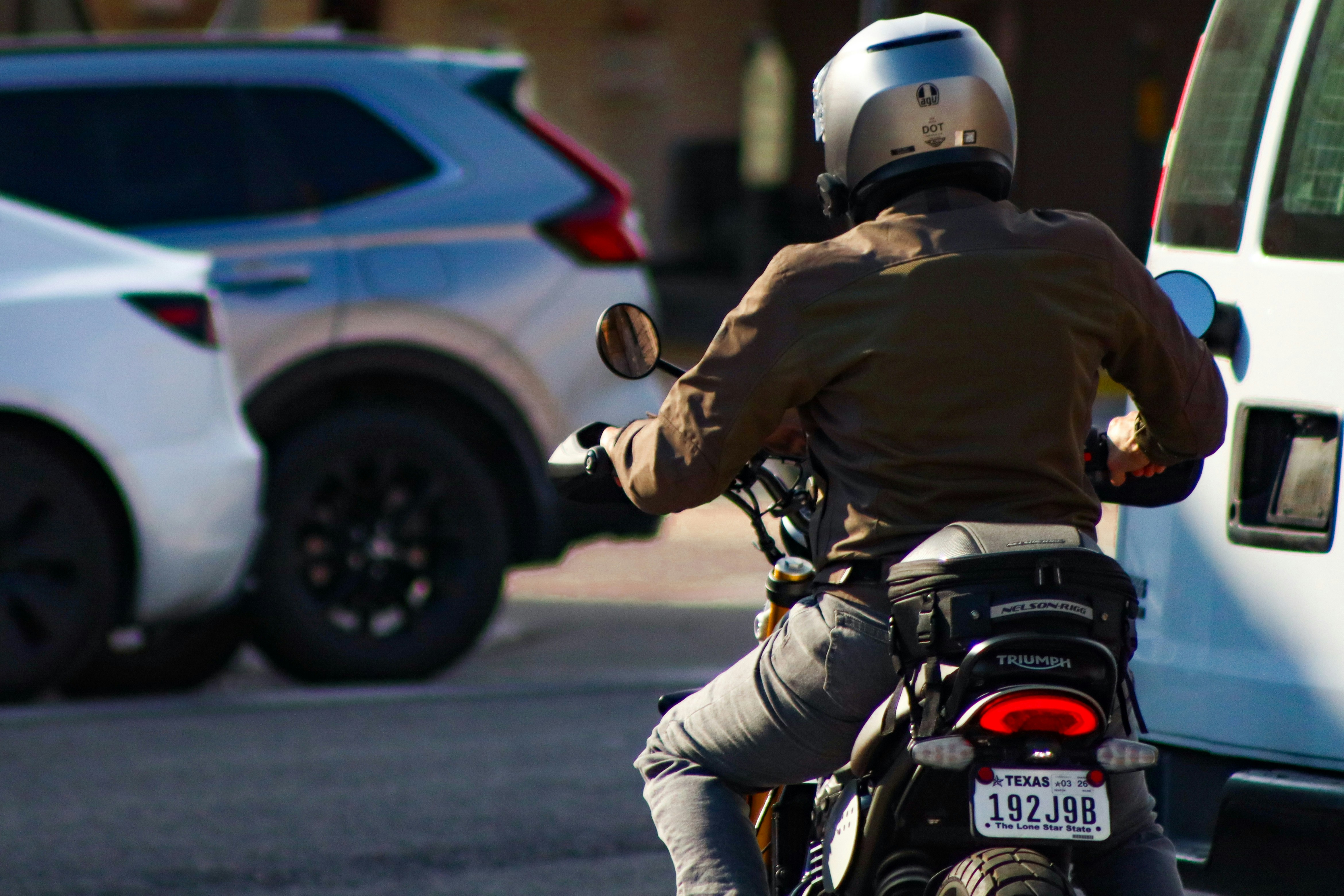 Motorcyclist wearing helmet rides between cars.
