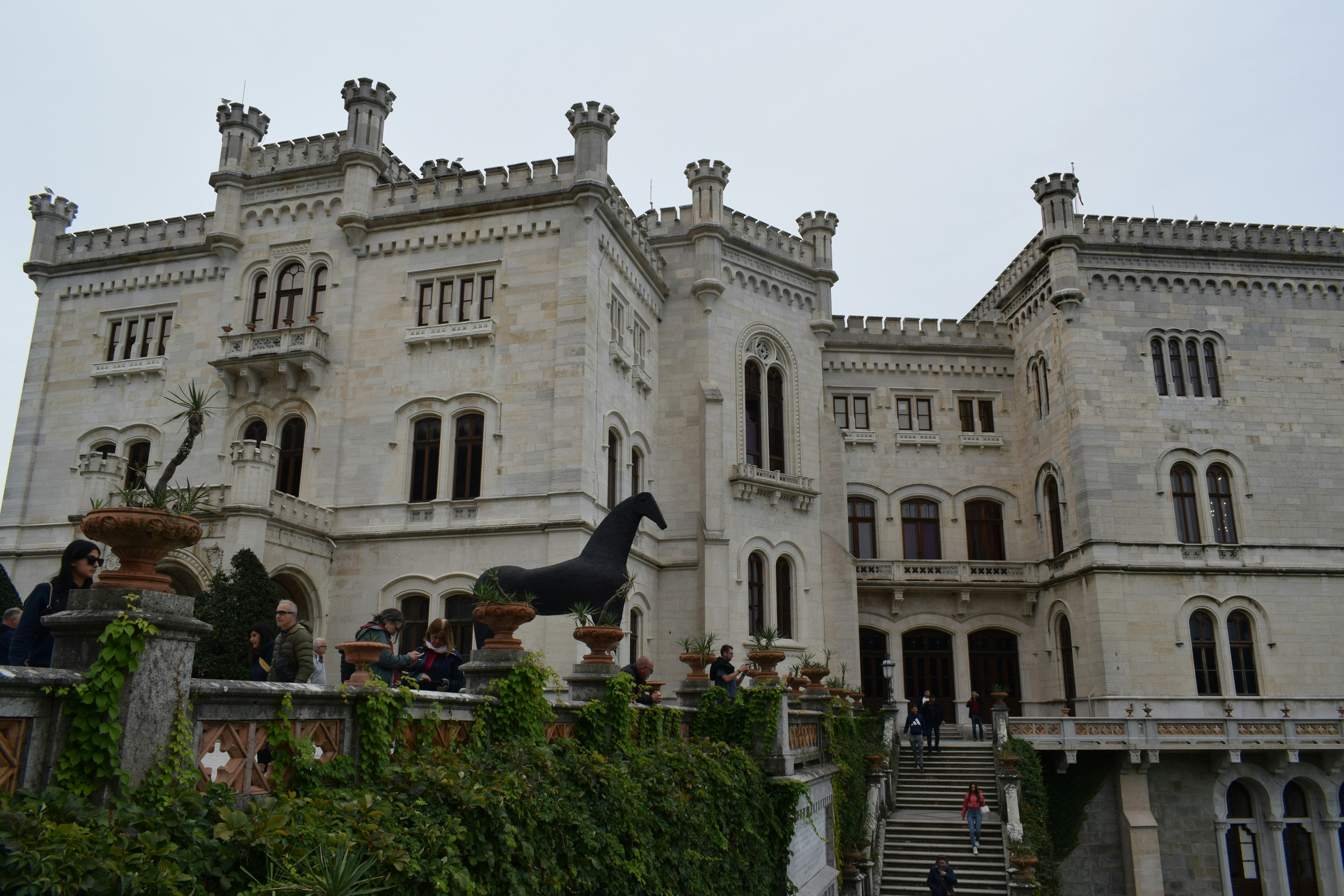 A grand white castle with a dark horse statue.