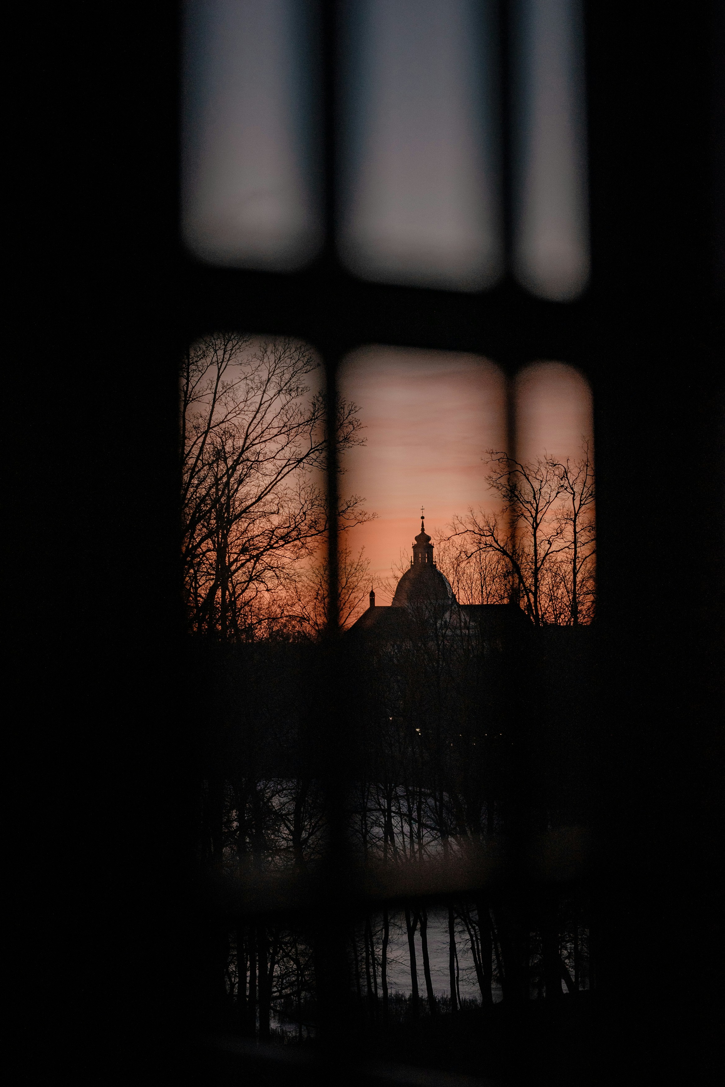 Silhouette of a domed building at sunset through window.
