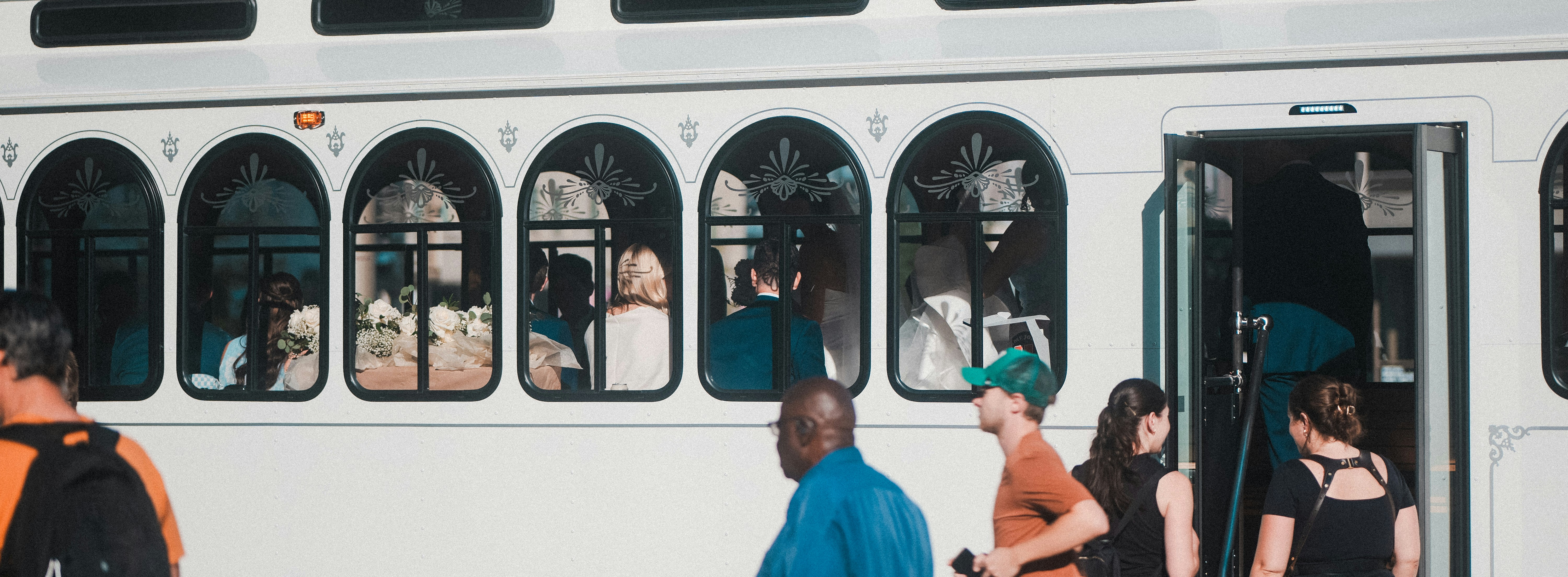 People boarding a trolley with arched windows.
