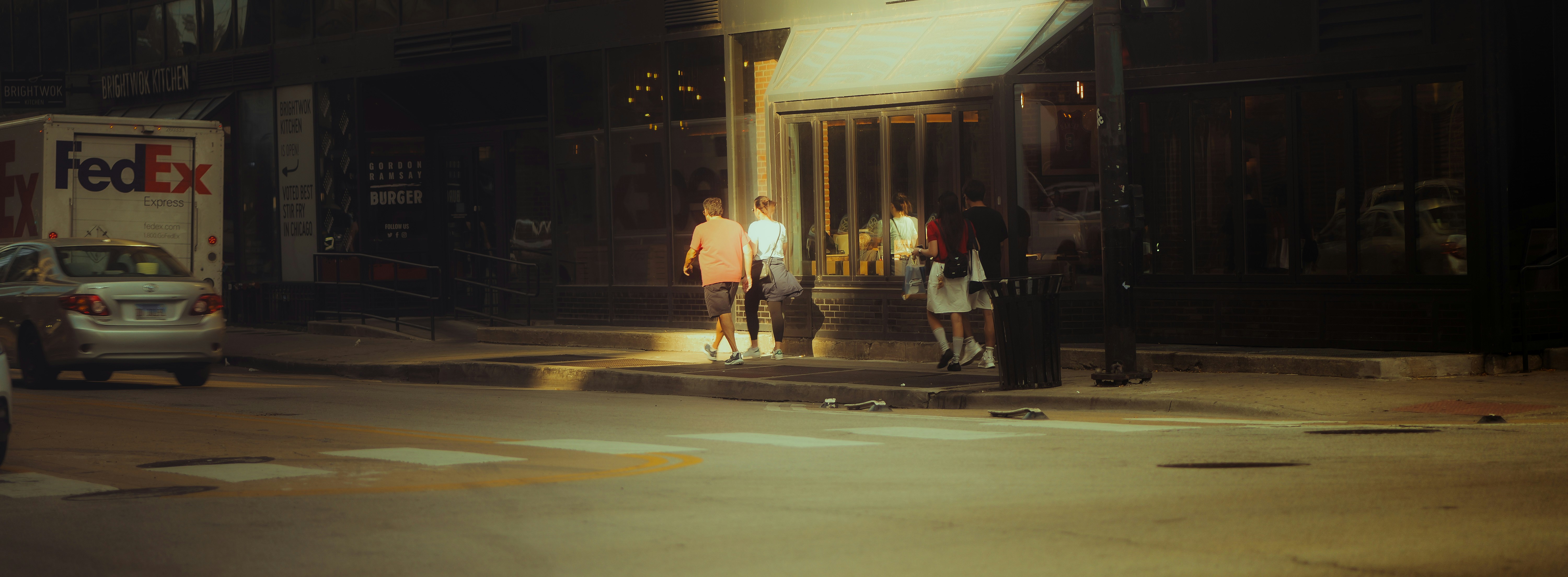 People walk by a fedex truck at night.