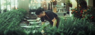 Man tending to lush green plants indoors.