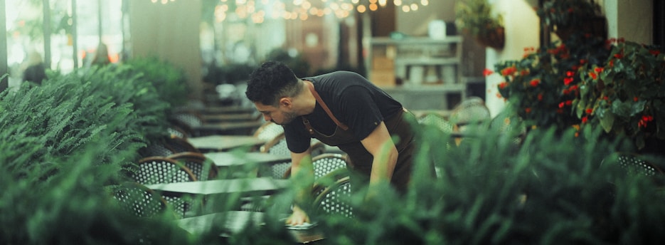Man tending to lush green plants indoors.