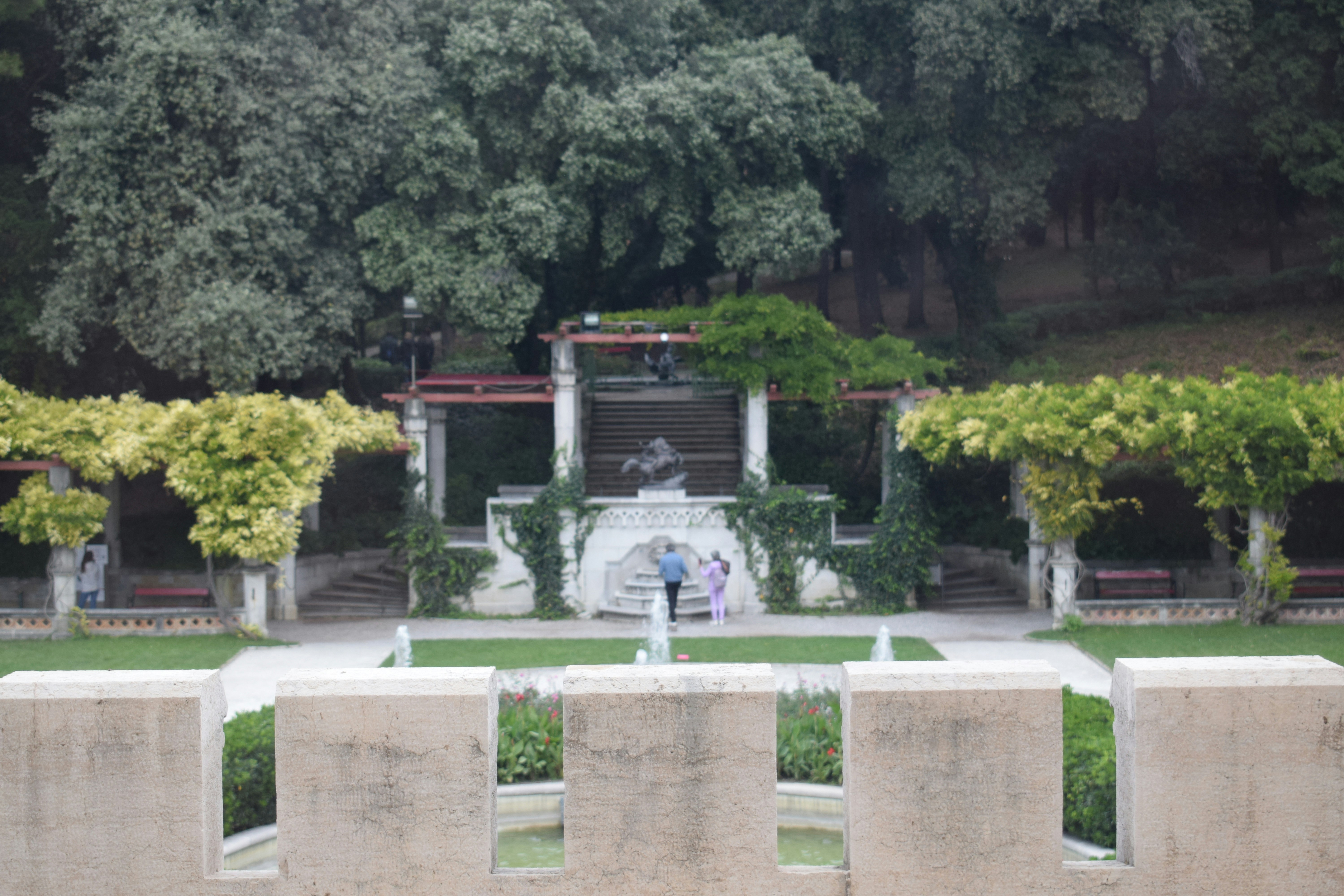 Ornate garden with a central fountain and statues.