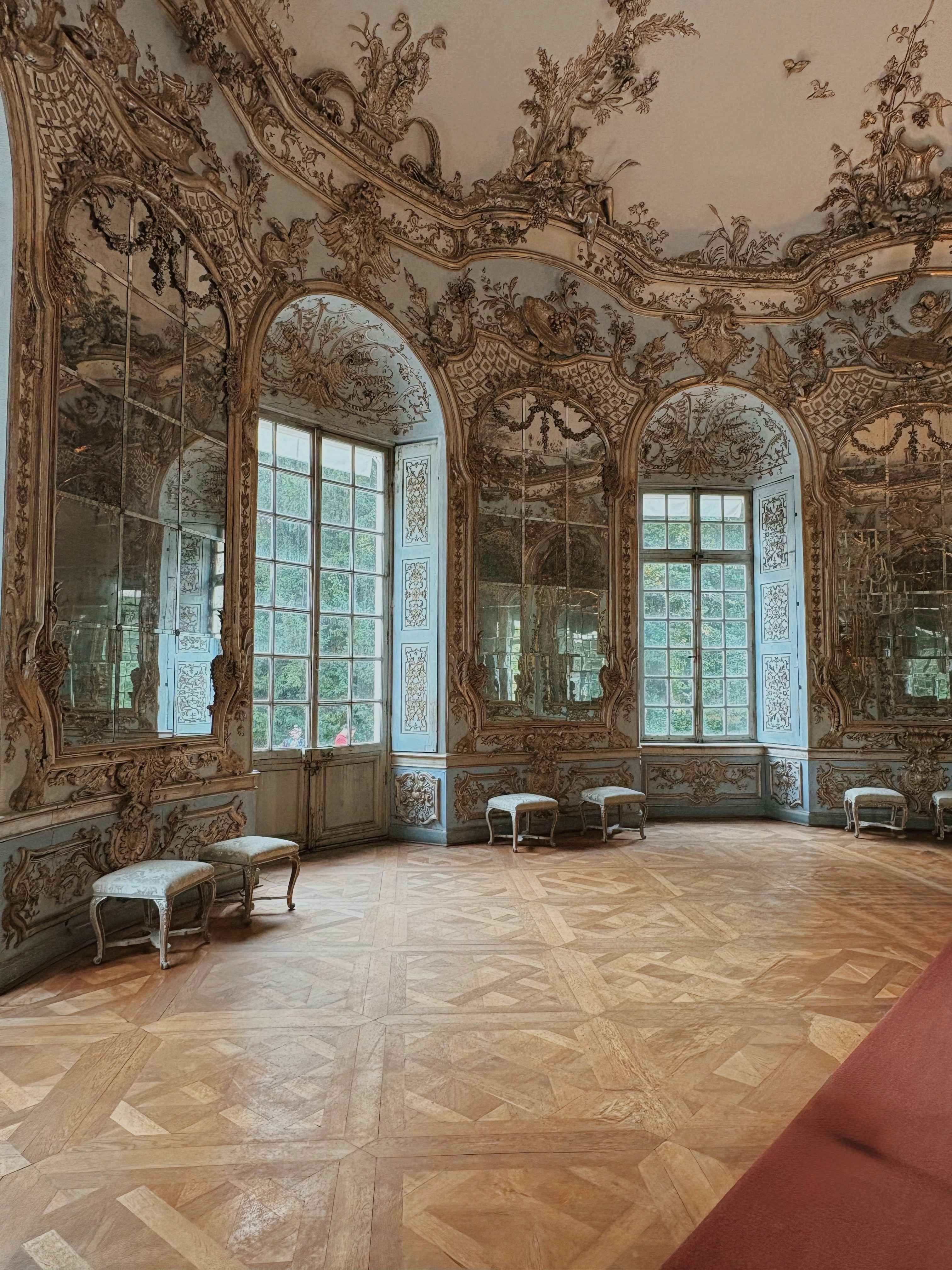 Ornate historic room with large windows and seating