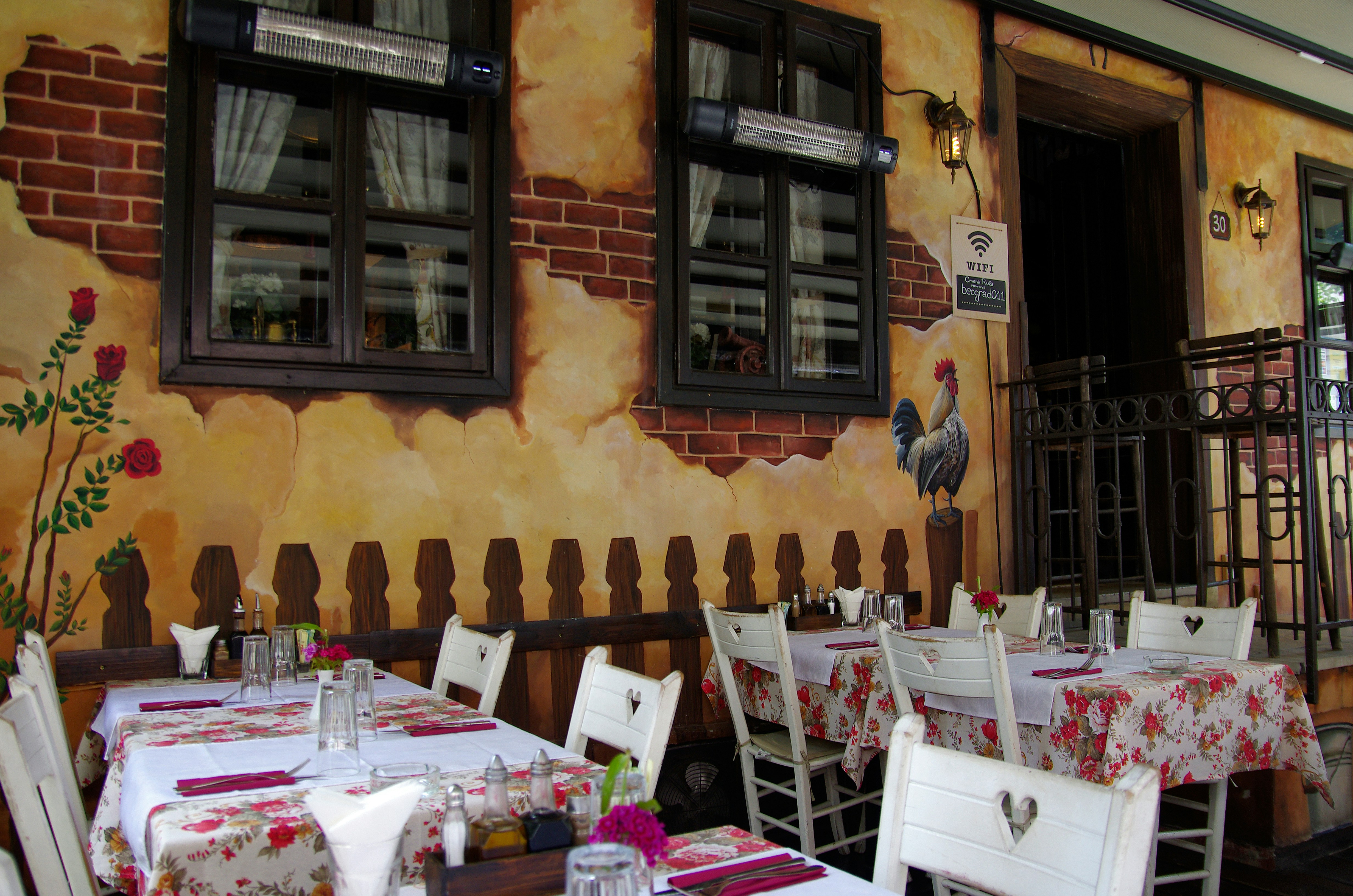 Outdoor restaurant tables with floral tablecloths and brick wall