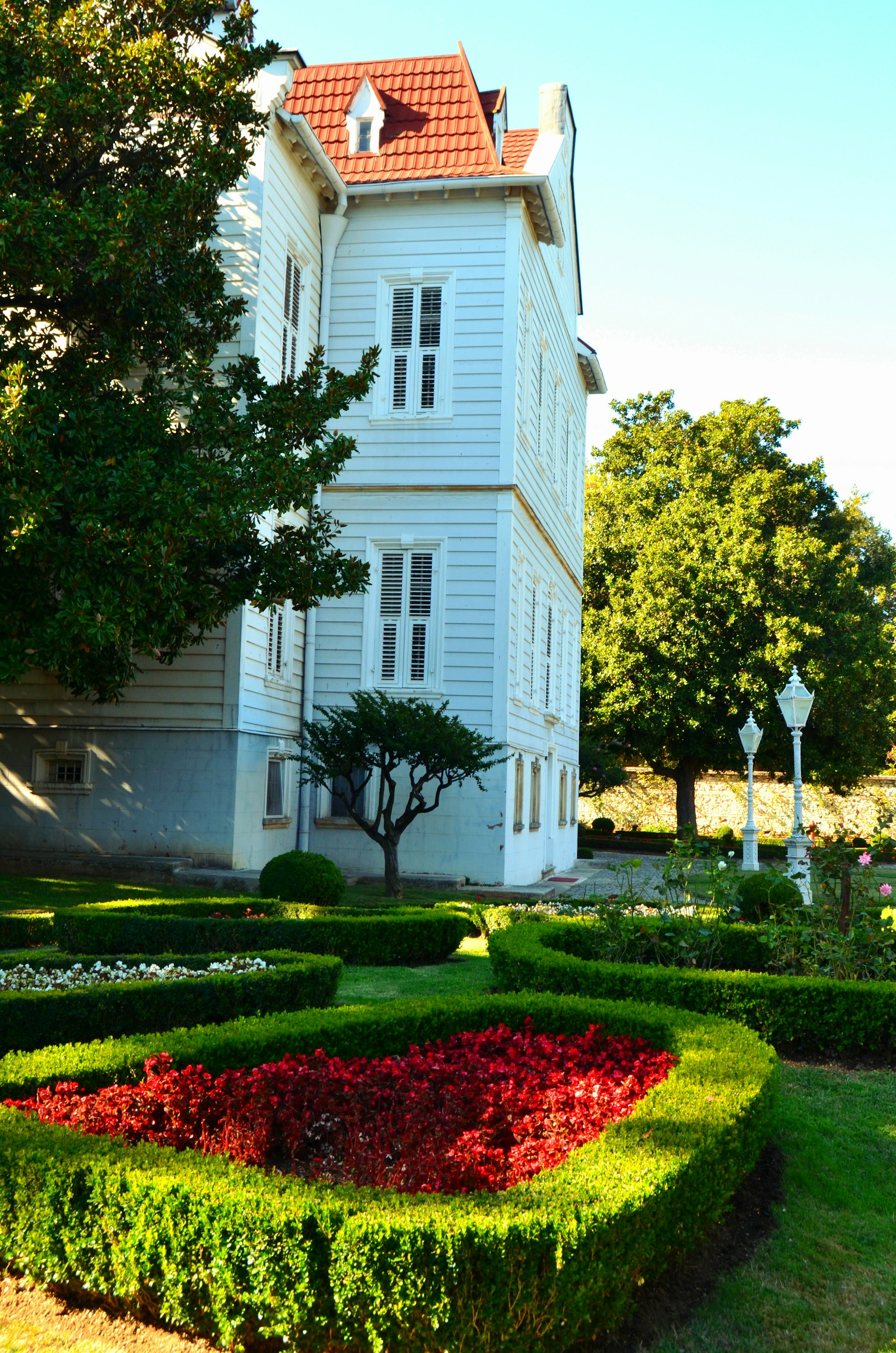 White historic building with manicured gardens and trees
