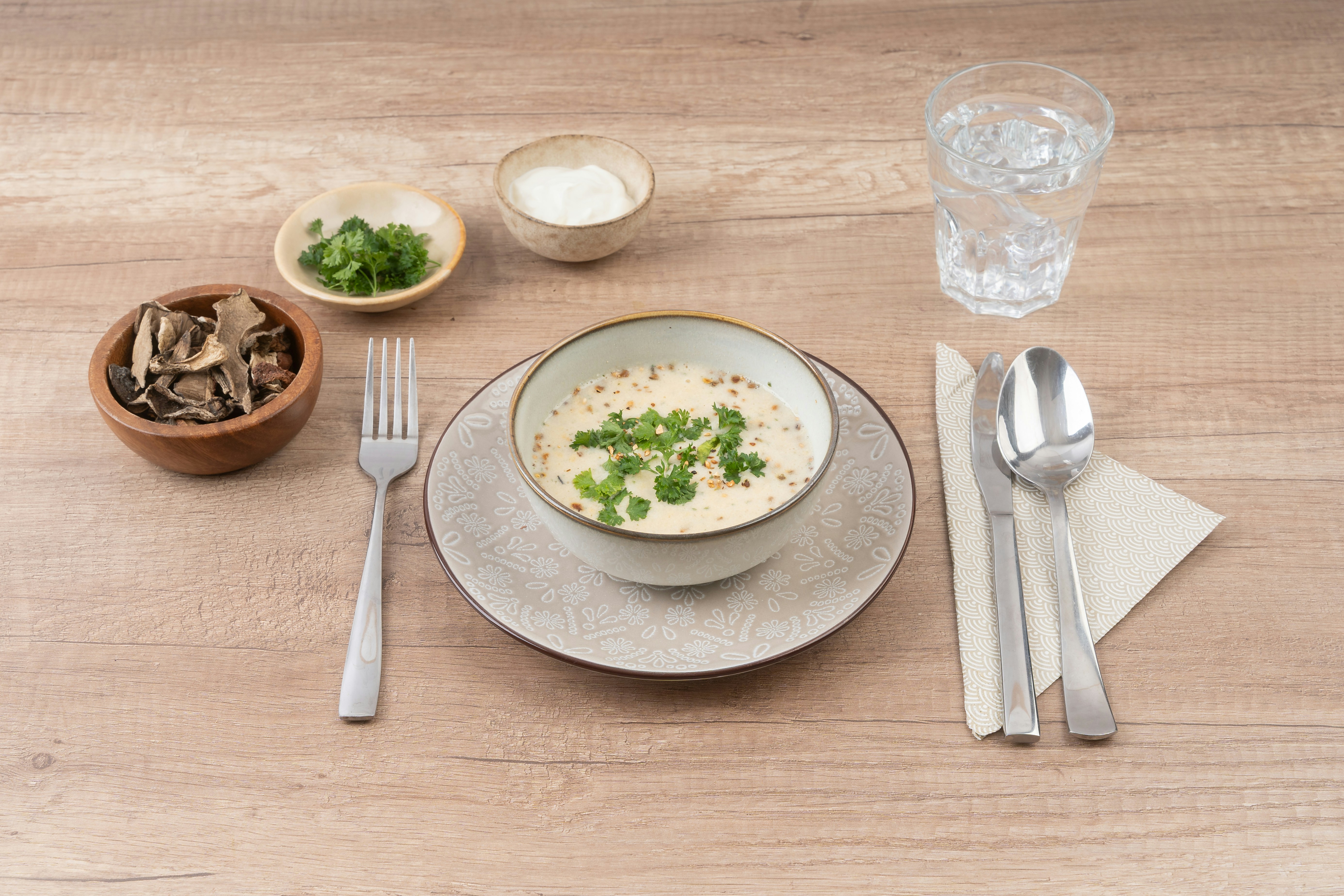 Bowl of soup with garnishes and drink on table