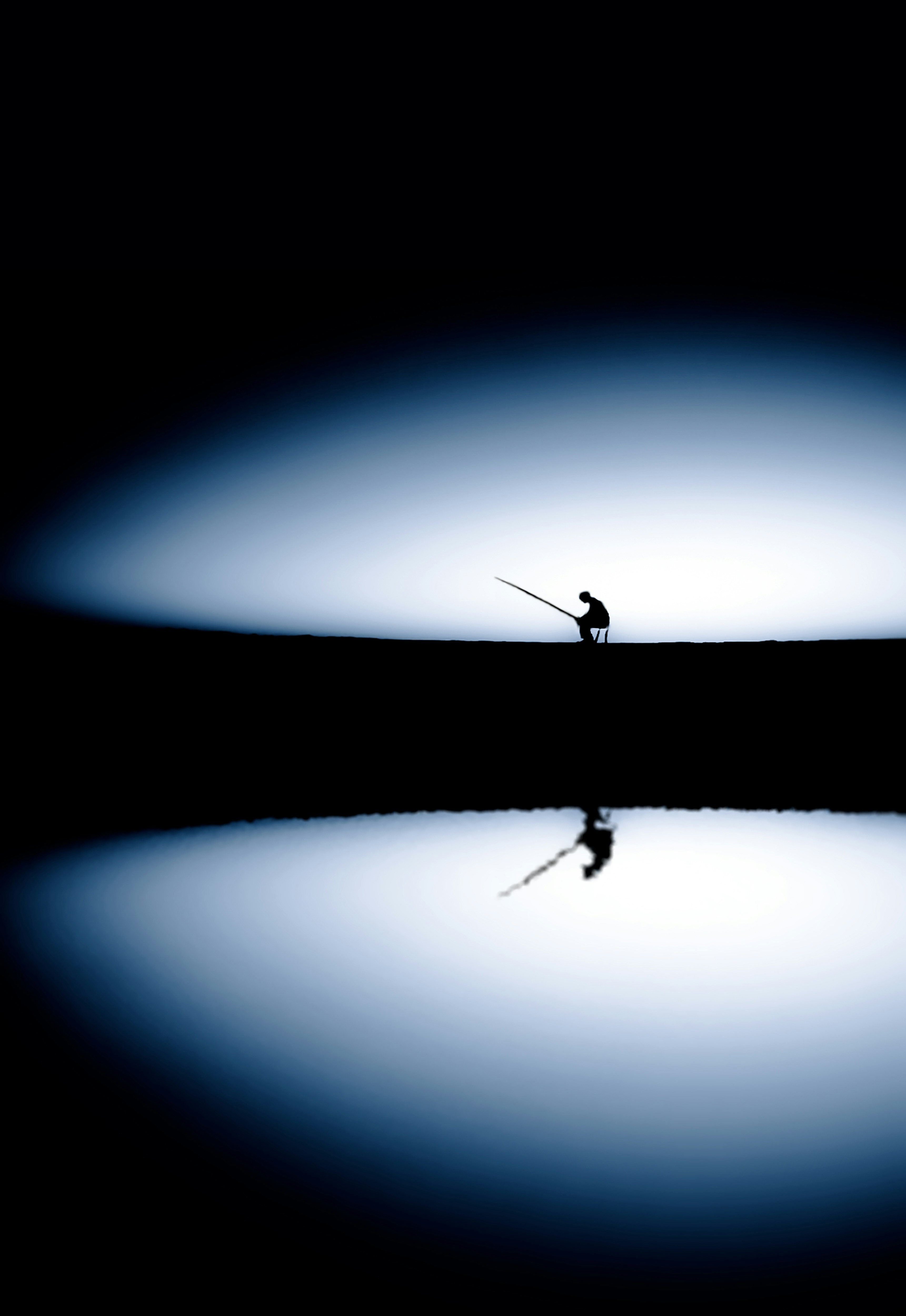 Silhouette of person fishing on calm reflective water
