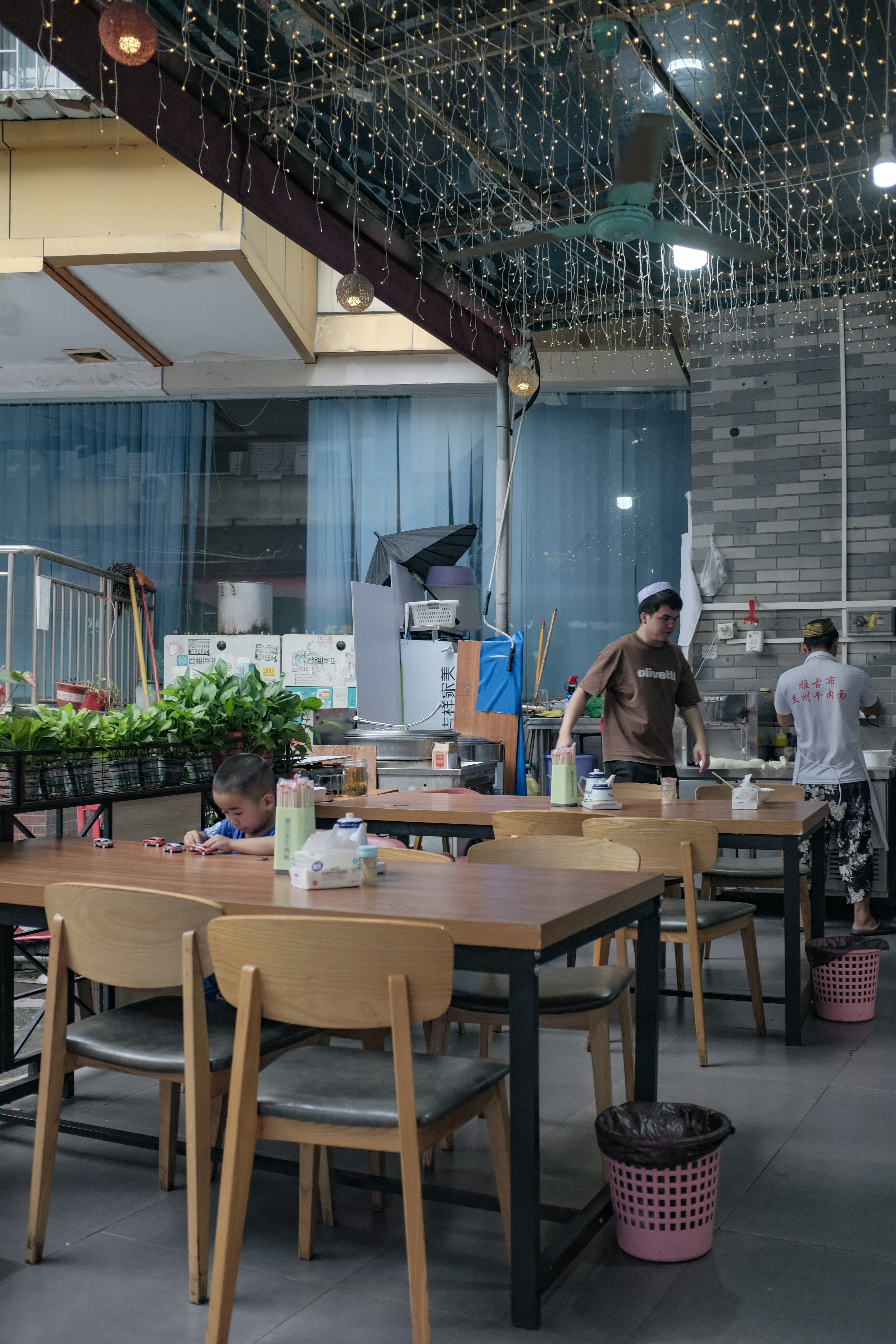 People in a restaurant with string lights overhead