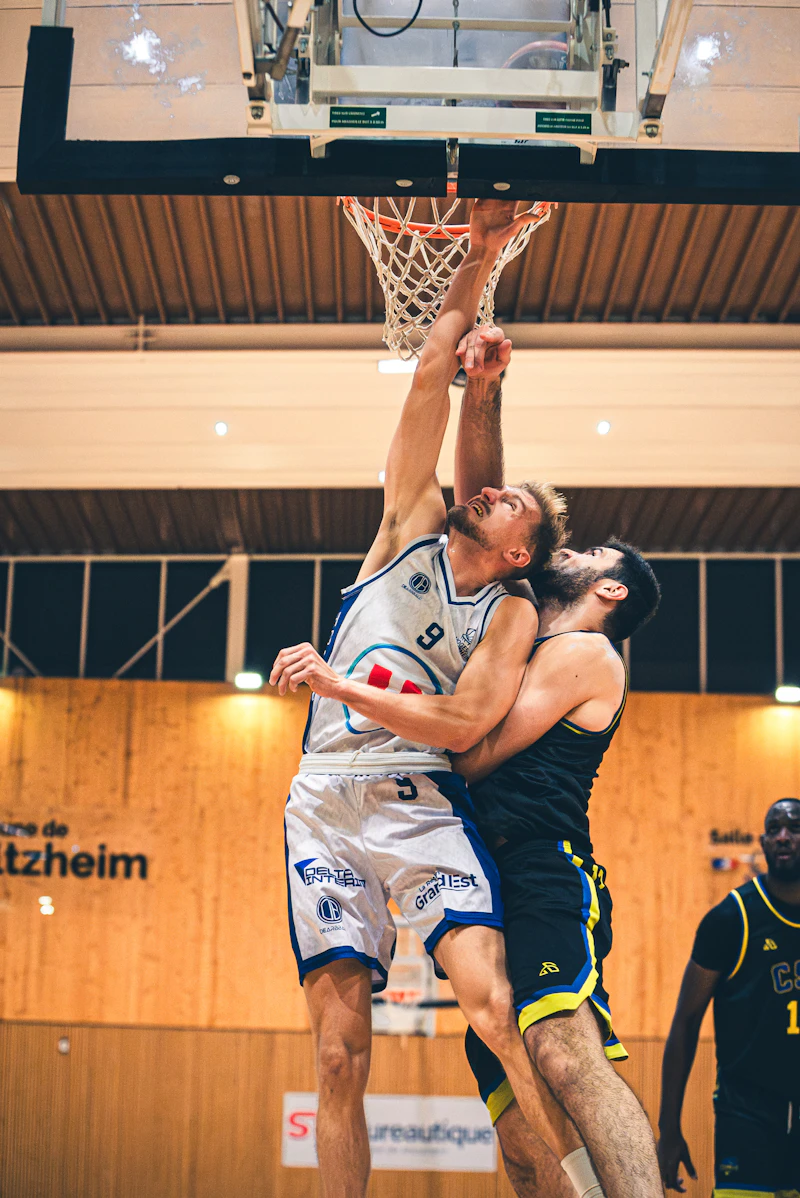 Two basketball players reaching for the ball