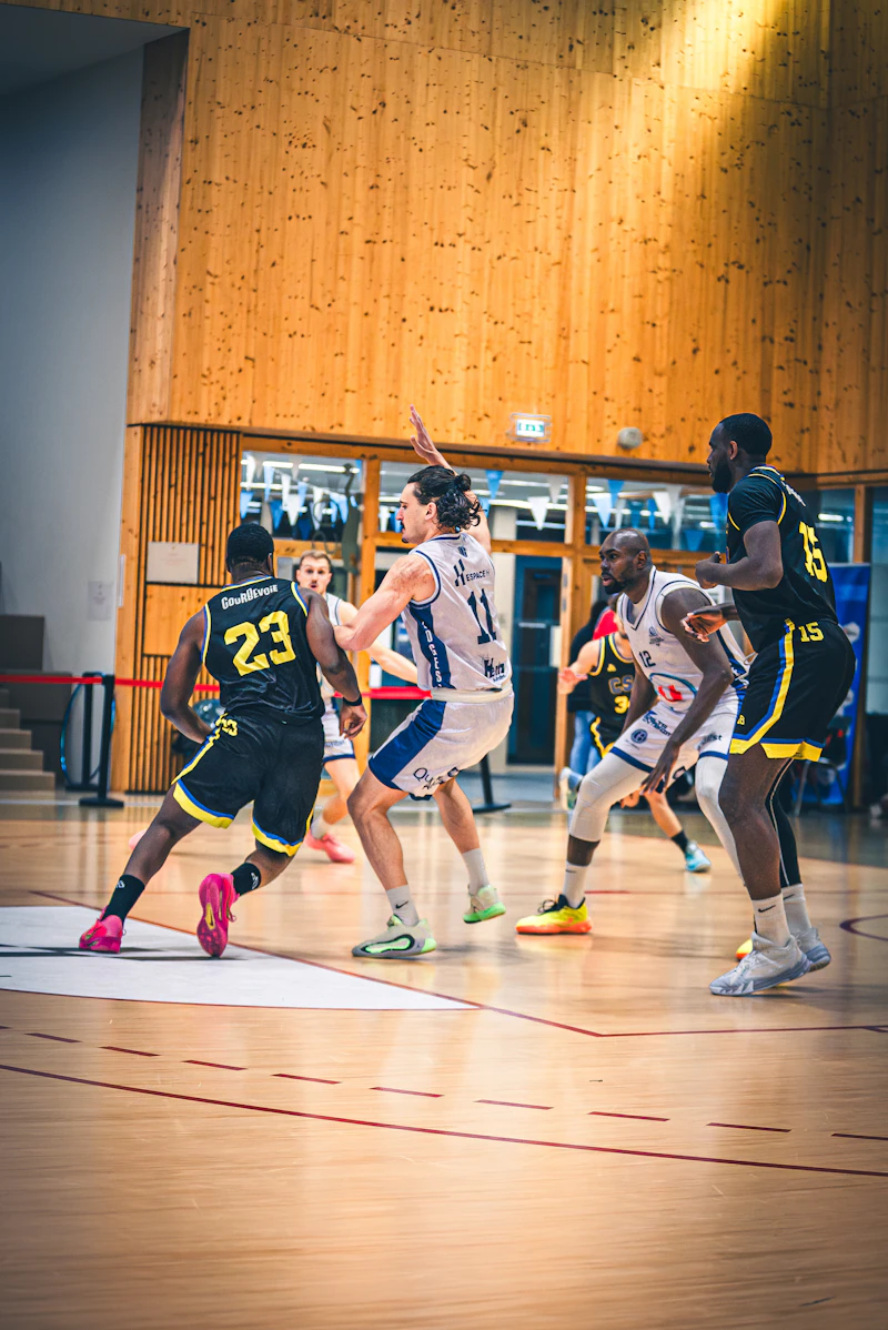 Basketball players competing on a wooden court indoors