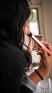 Woman applying makeup with a brush and compact.