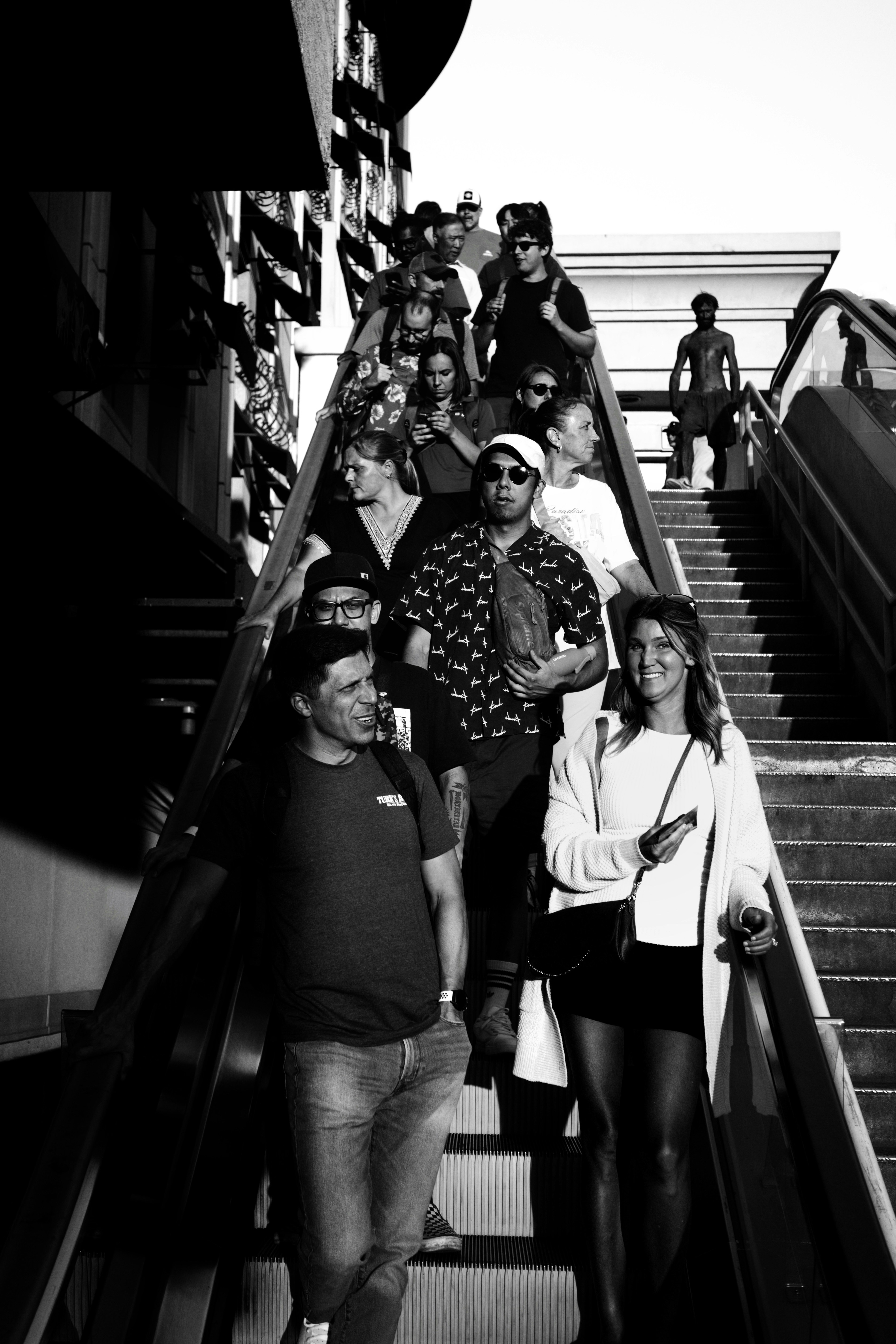 흑백으로 에스컬레이터를 타고 올라가는 사람들.