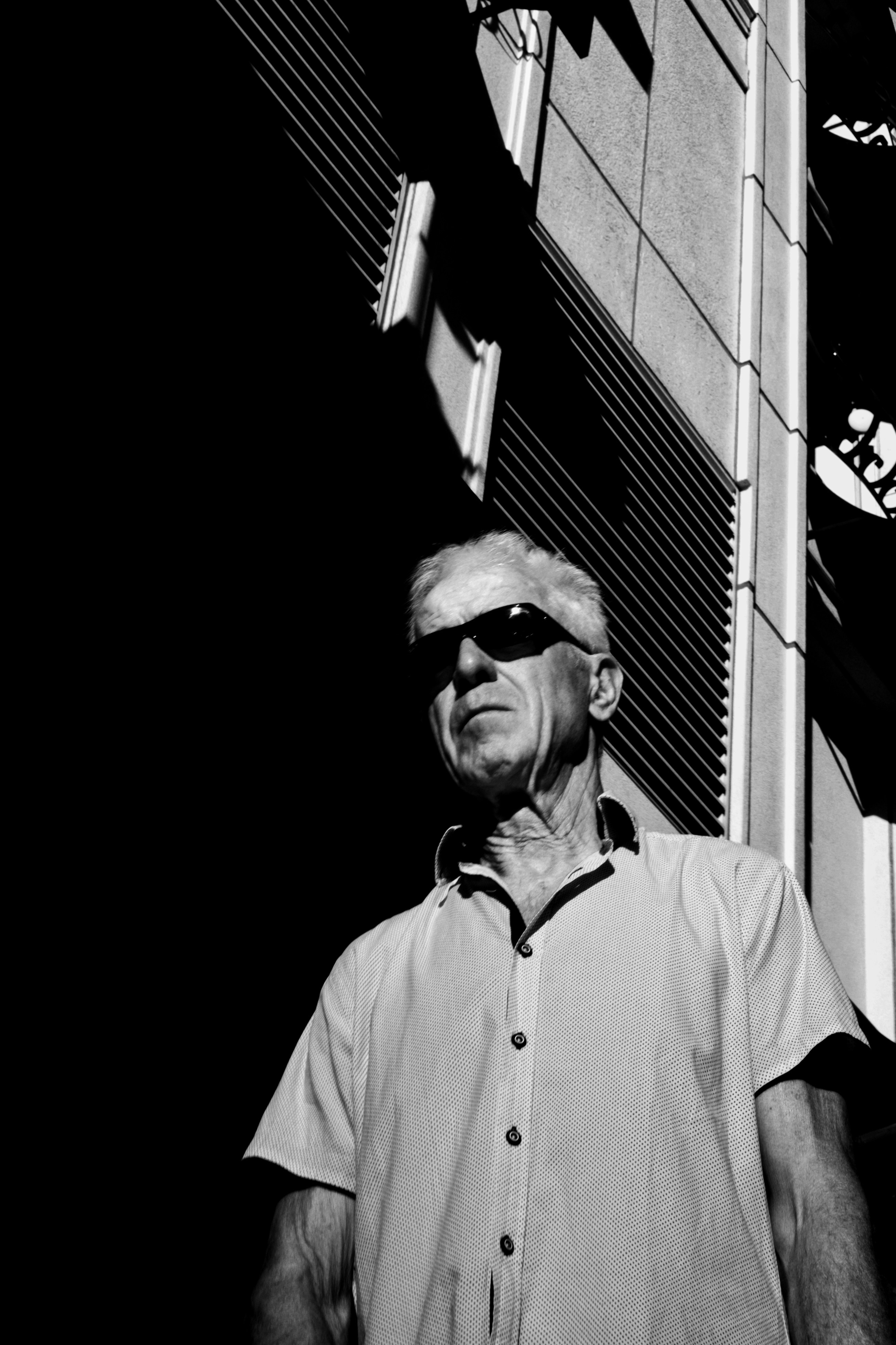 어둡고 그늘진 건물을 배경으로 선글라스를 쓴 남자.